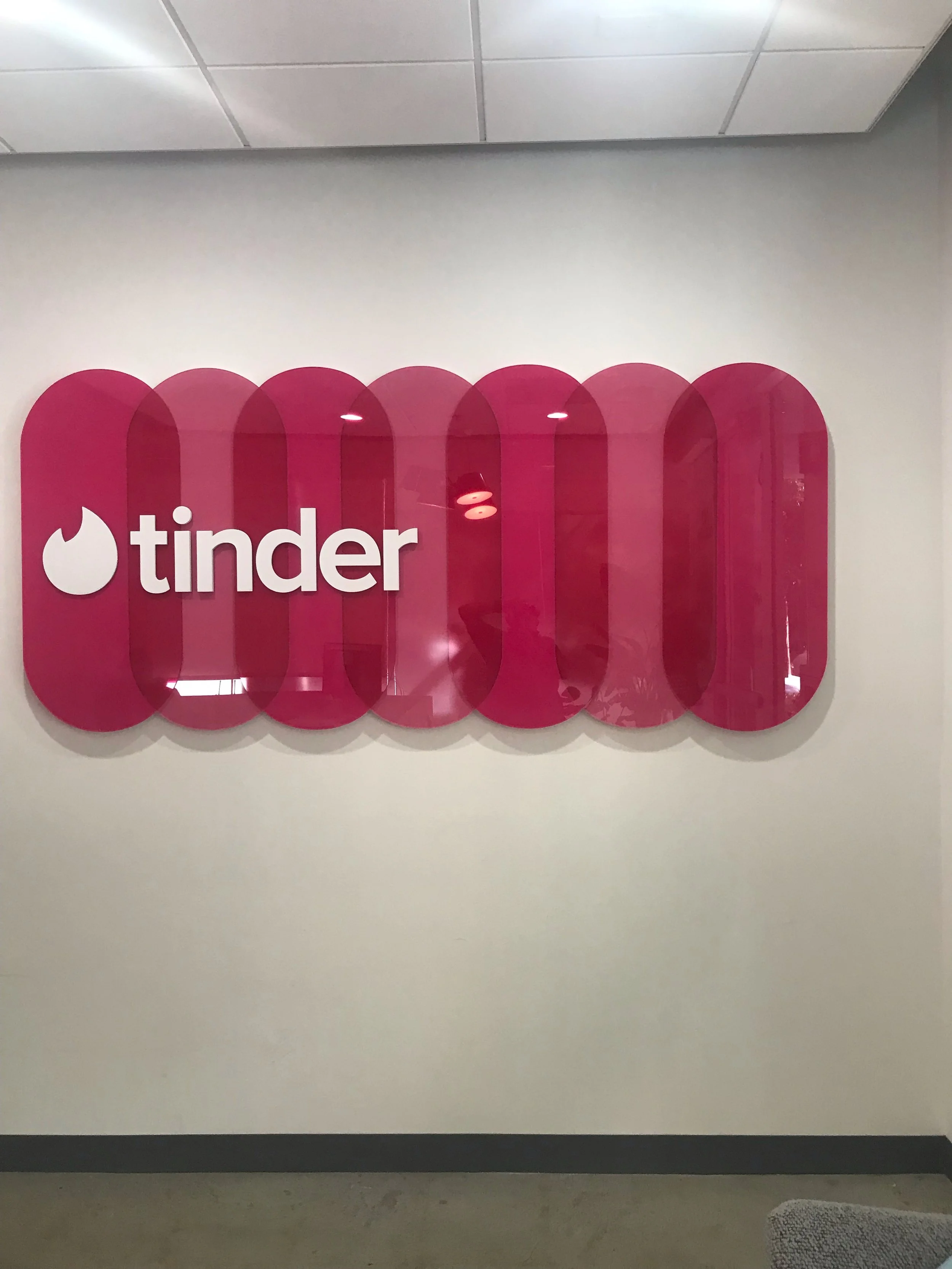 Dimensional Tinder logo signage creating a bold branded feature in corporate workplace