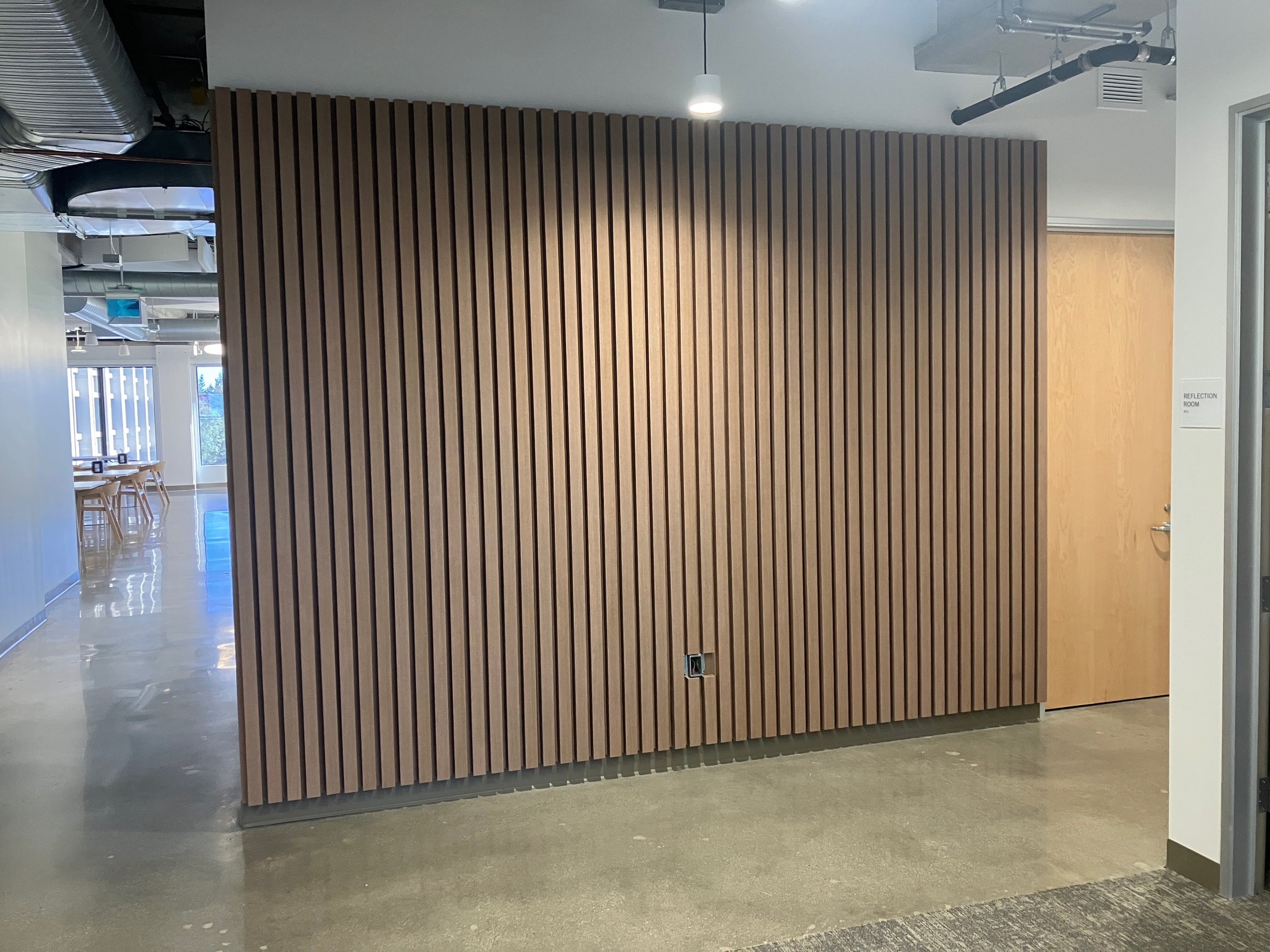 Arete wood slat acoustic feature wall installed in a commercial office interior, providing sound absorption and a modern architectural wood finish.