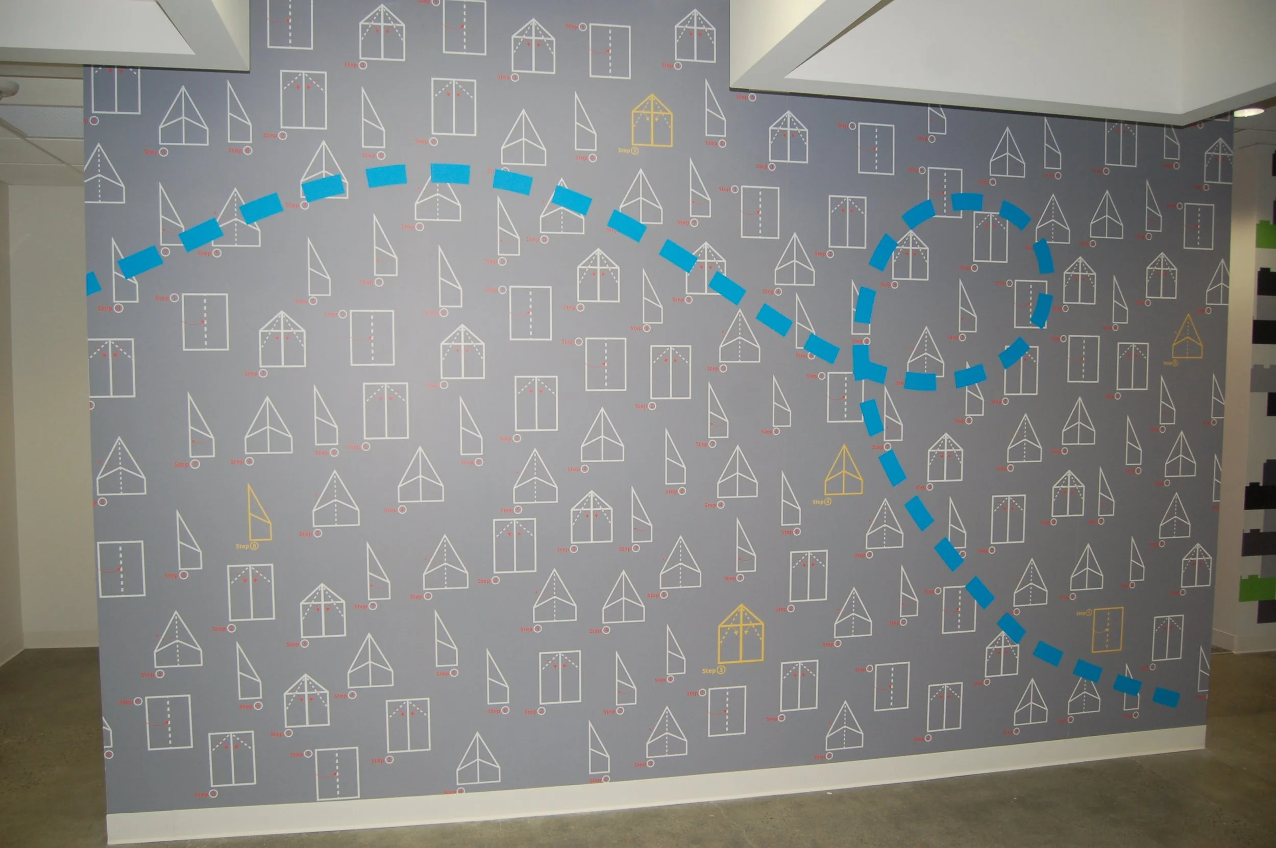 Custom wayfinding wall graphic with directional elements installed in a commercial hallway.