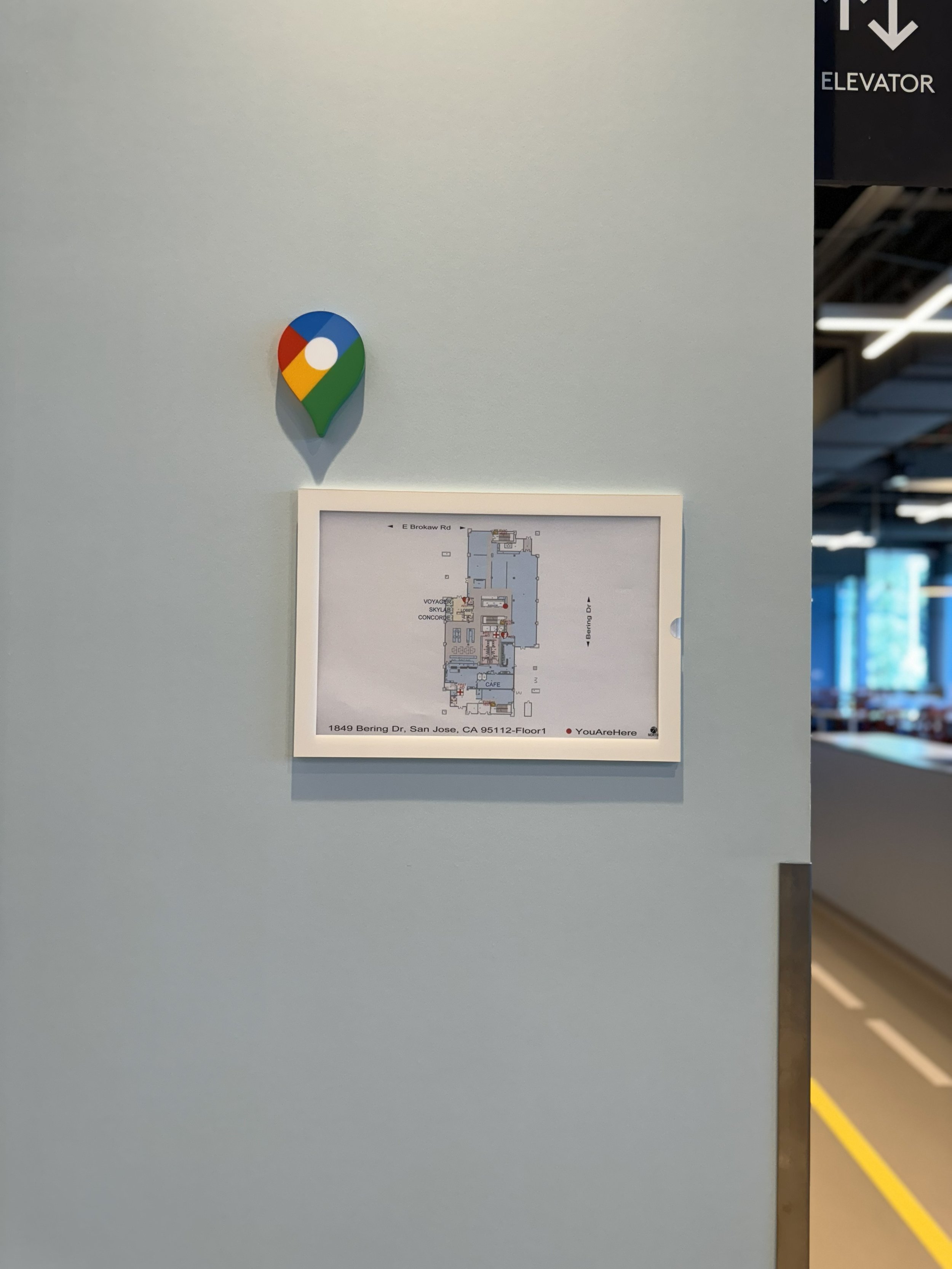 Installed wayfinding location marker above framed floor plan for corporate office navigation and building orientation.