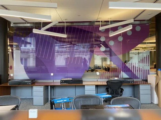 Glass film installation in progress at eBay New York office showing purple branded environmental graphics being applied to workplace glazing