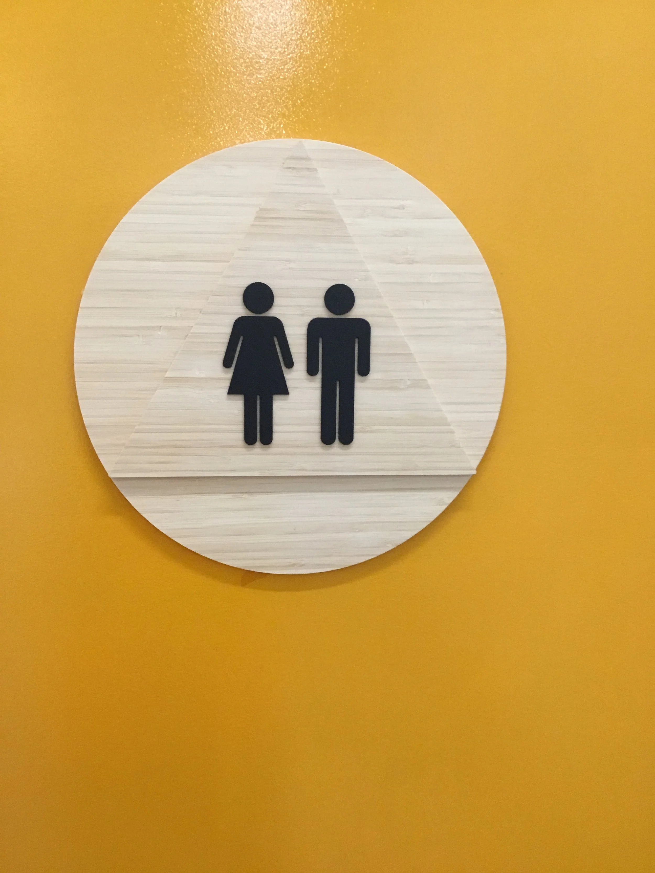 Restroom identification signage with dimensional icons installed to provide clear wayfinding in commercial workplace environment