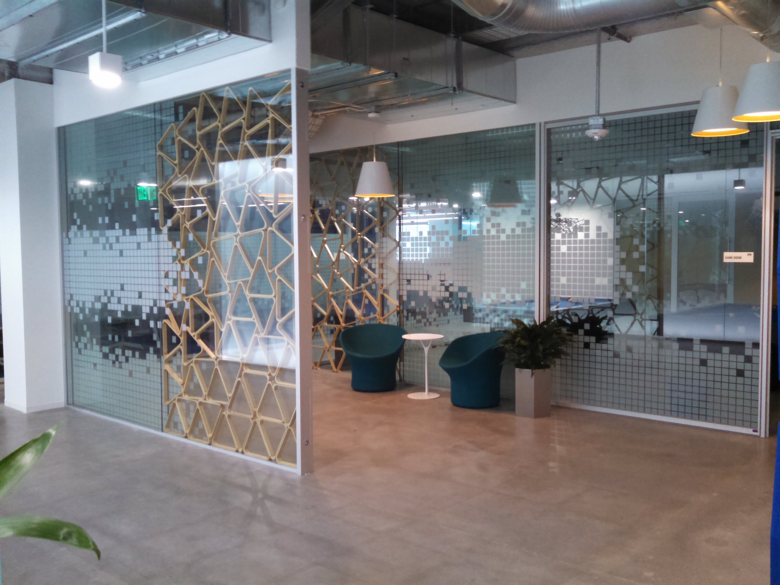 Custom decorative window film with patterned cutouts creating visual interest and partial privacy in a workplace.