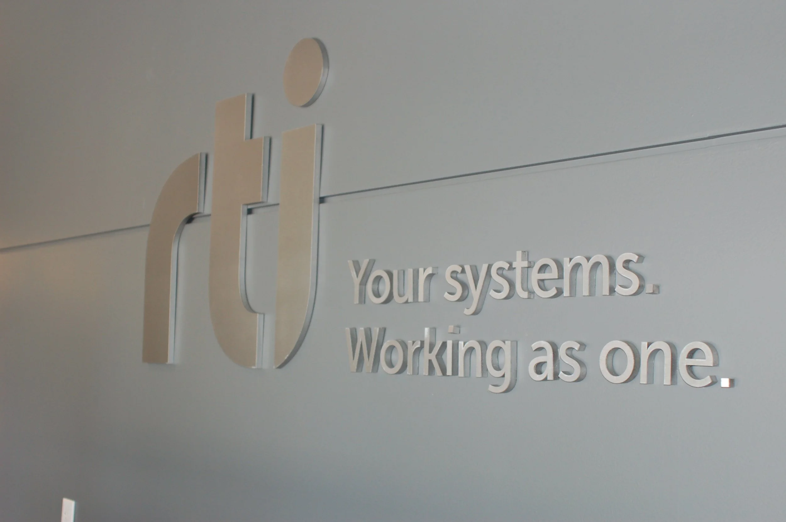 Dimensional RTI logo signage installed to create a clean branded feature in corporate workspace