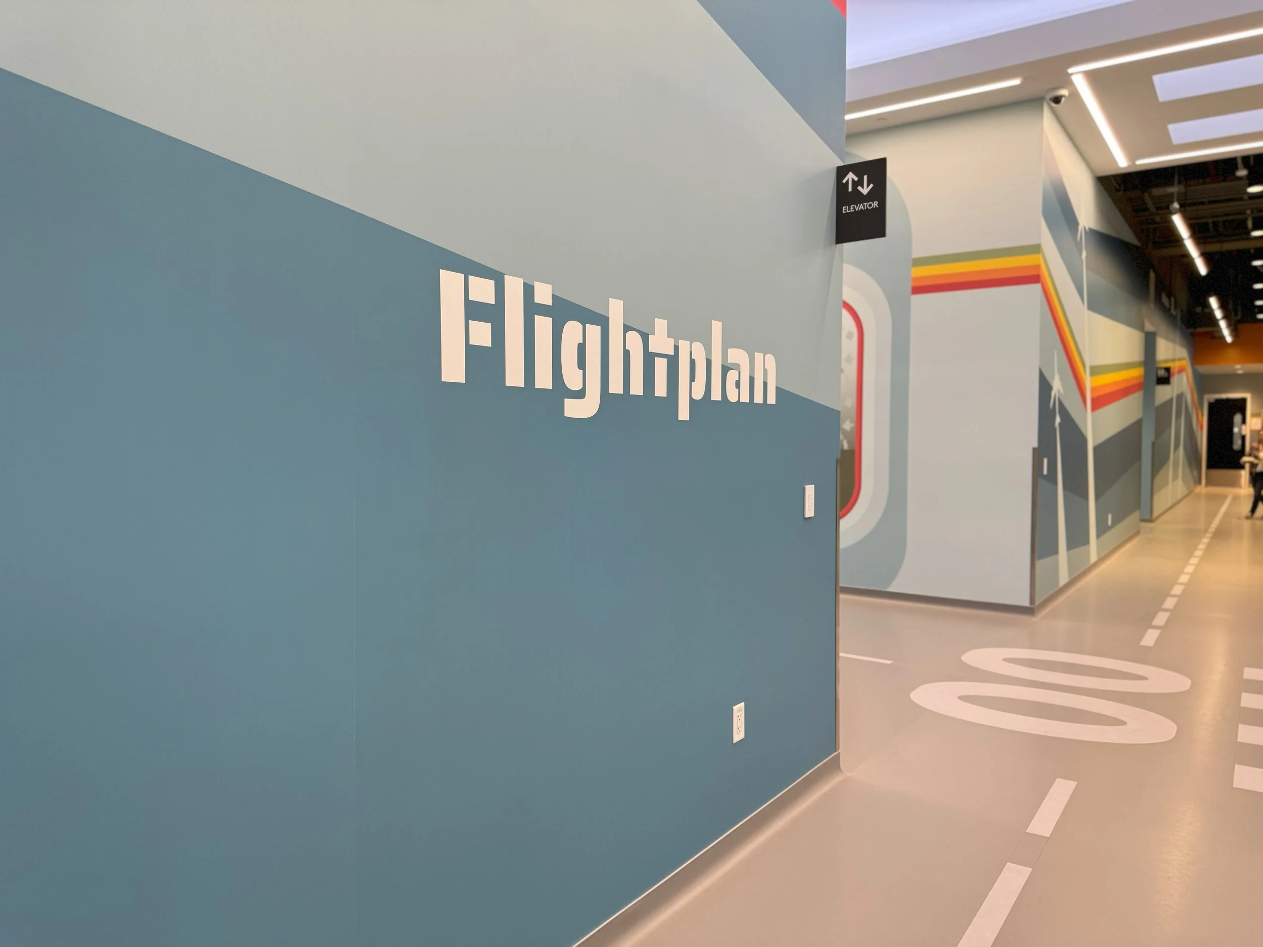 Branded wall graphics with department identification supporting clear navigation within the workplace.