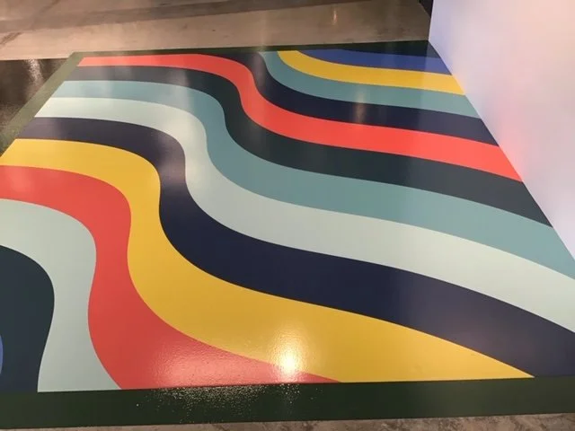 Large-scale branded floor graphics with bold color patterns creating a visual feature in corporate environment