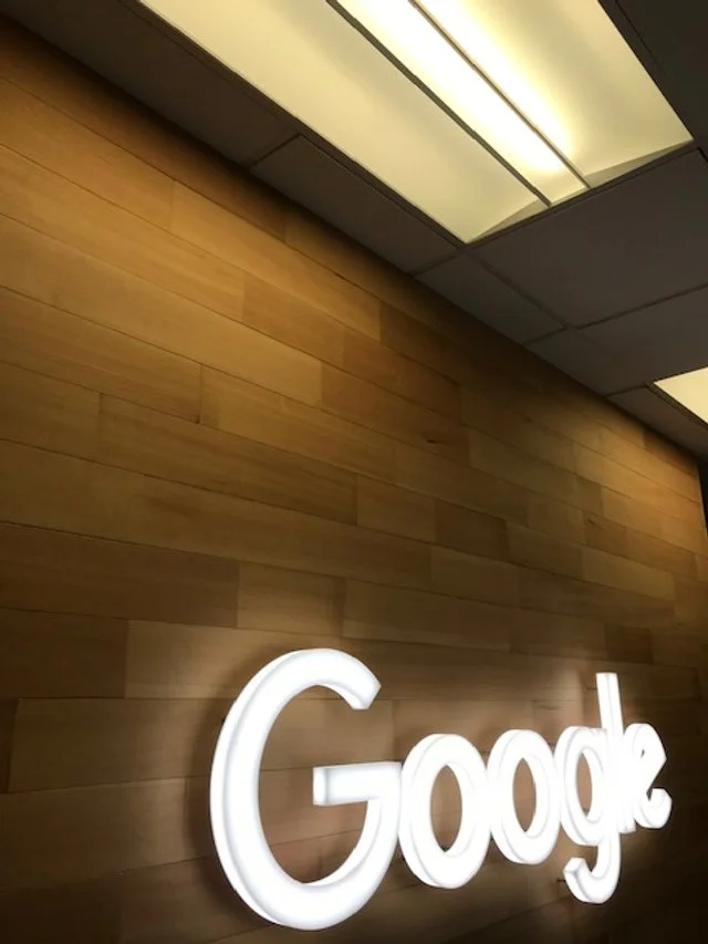 Illuminated corporate logo mounted on natural wood feature wall in office environment