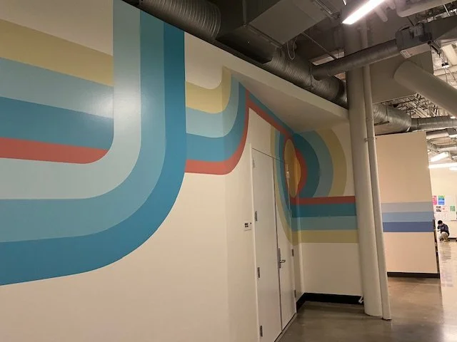 Custom environmental graphics installation wrapping commercial staircase and adjacent wall in modern office space