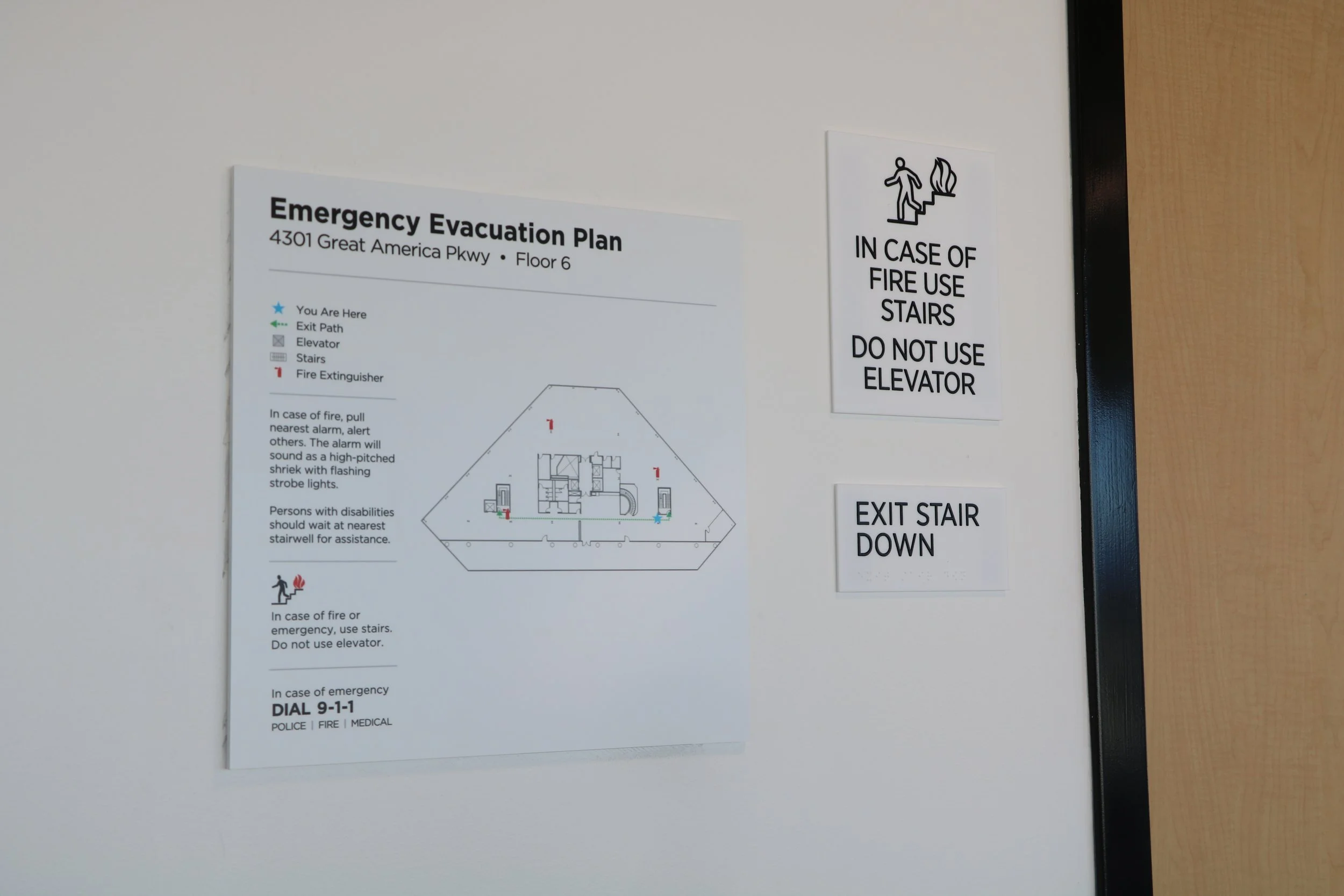 ADA-compliant emergency evacuation signage and fire safety wayfinding installed in commercial office building hallway.