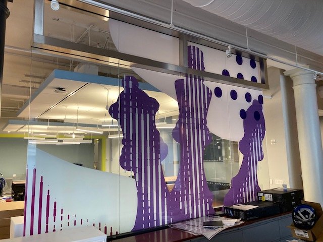 Glass film installation in progress at eBay New York office showing purple branded environmental graphics being applied to workplace glazing