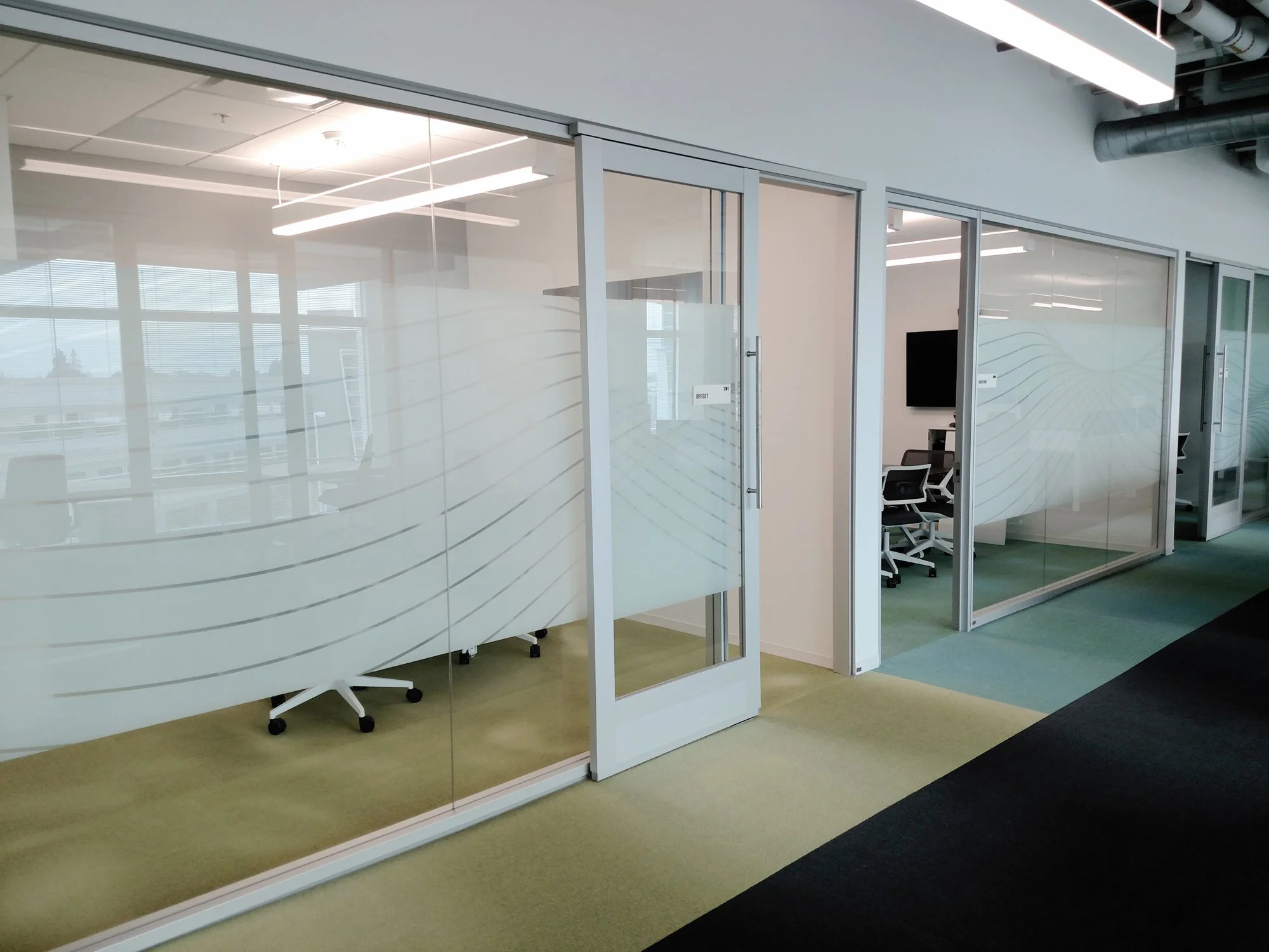 Frosted privacy window film installed on glass office partitions for conference room privacy and clean architectural design.