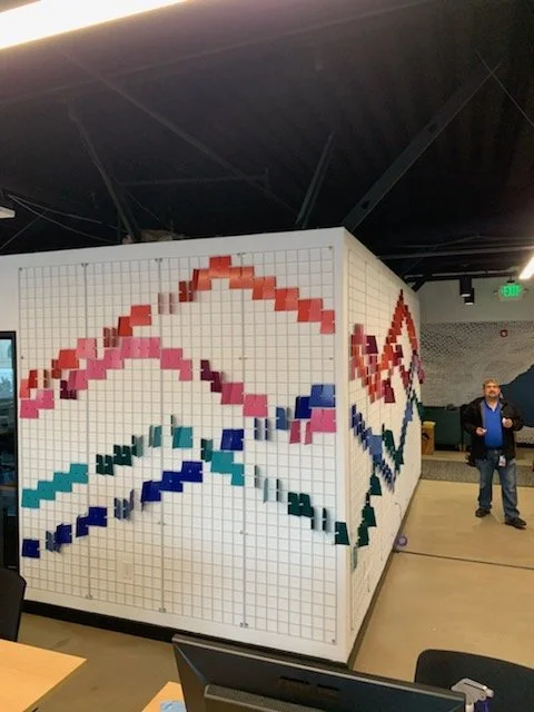 Large-scale dimensional wall installation transforming a corridor with custom geometric elements and brand-inspired color.