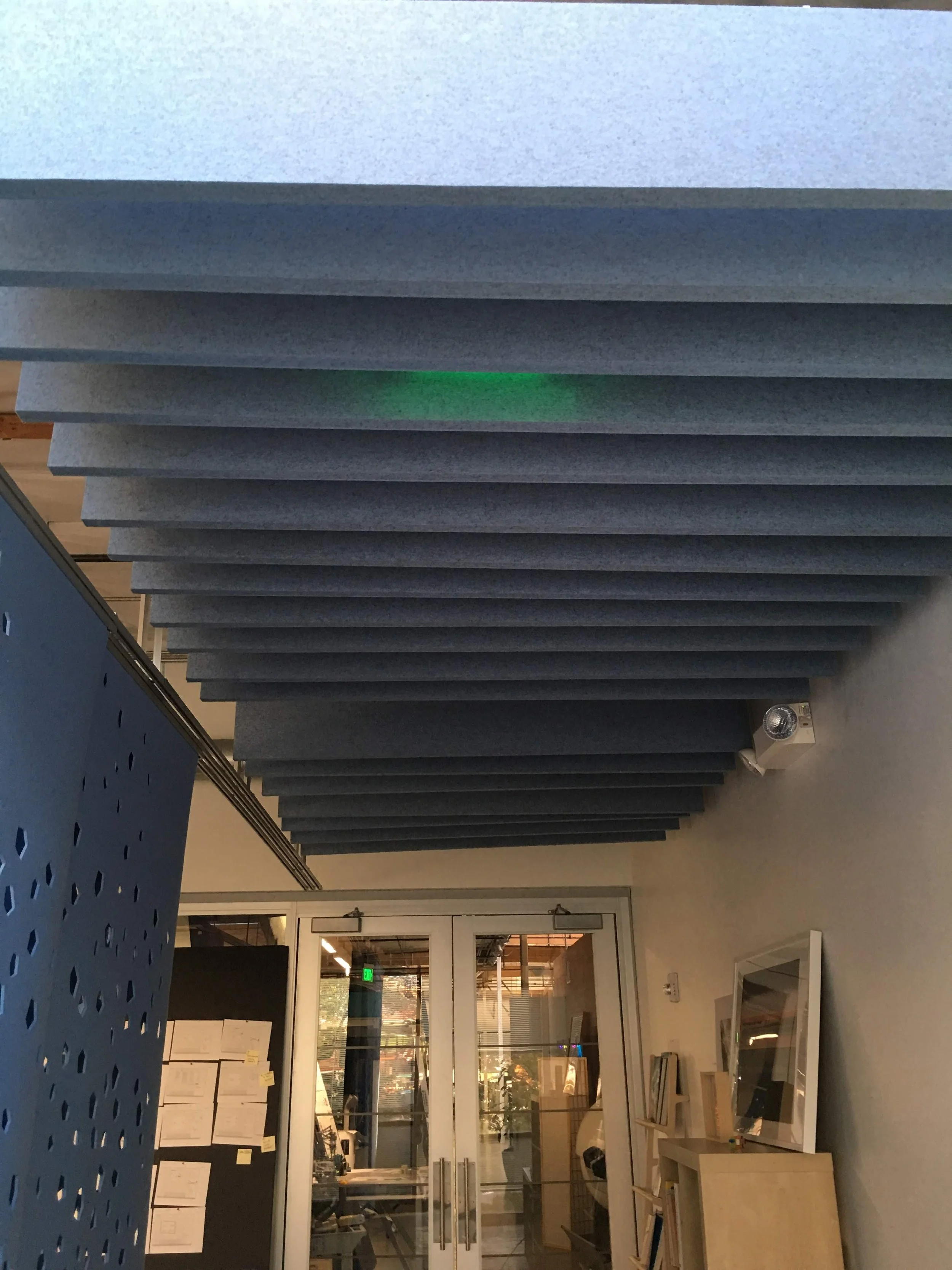 Linear acoustic ceiling baffles reducing noise and improving sound performance in hallway