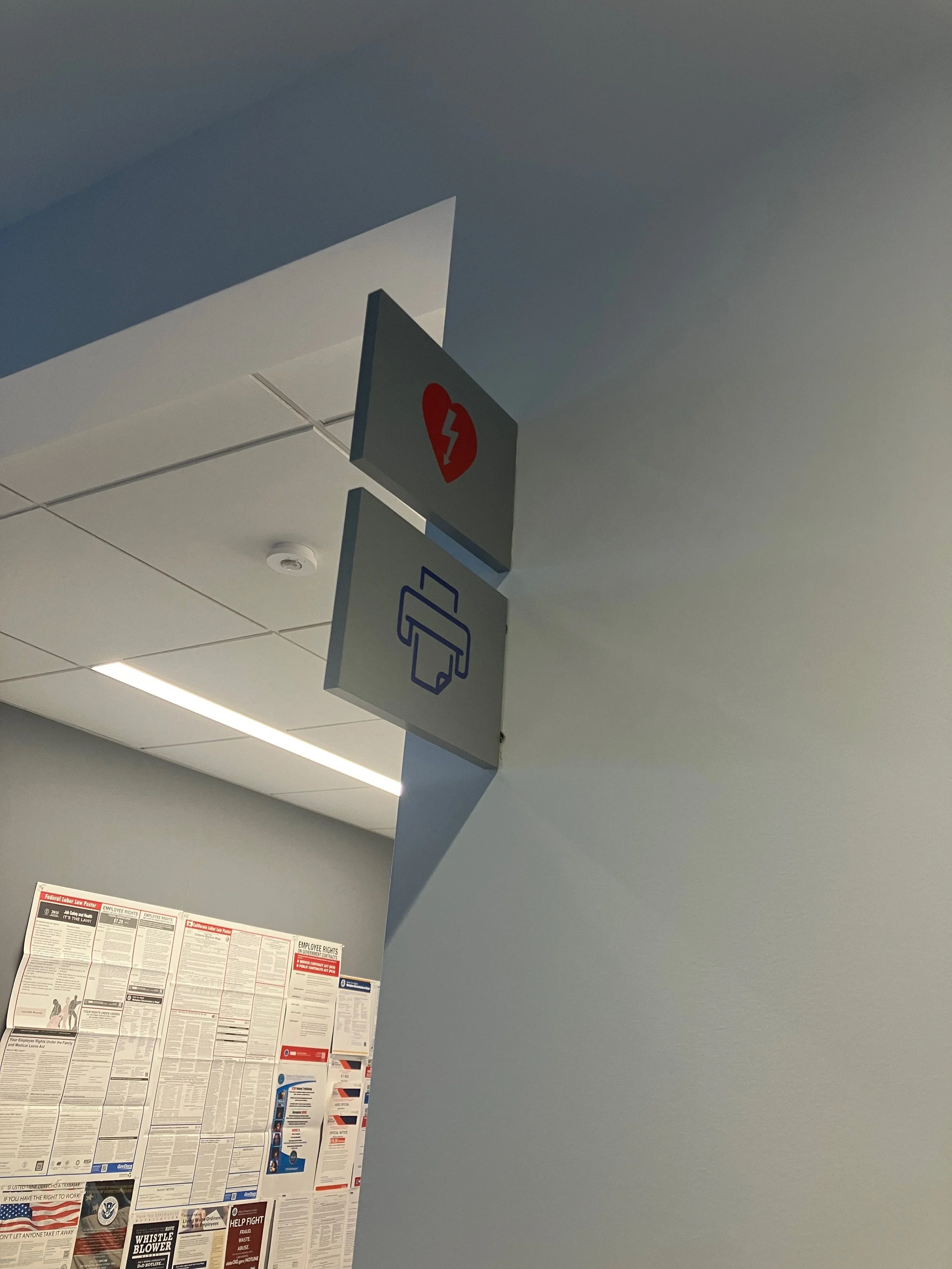 Flush-mounted fire extinguisher blade sign adjusted for proper alignment and code-compliant installation at the KPMG San Jose office.