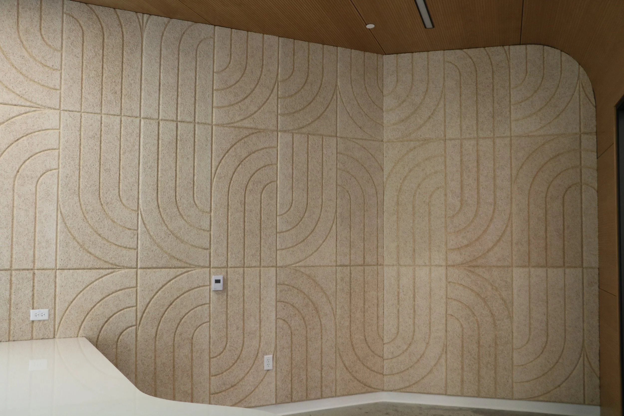 BAUX Wood Wool Curve acoustic feature wall with geometric pattern installed in modern commercial interior for noise reduction and design impact.