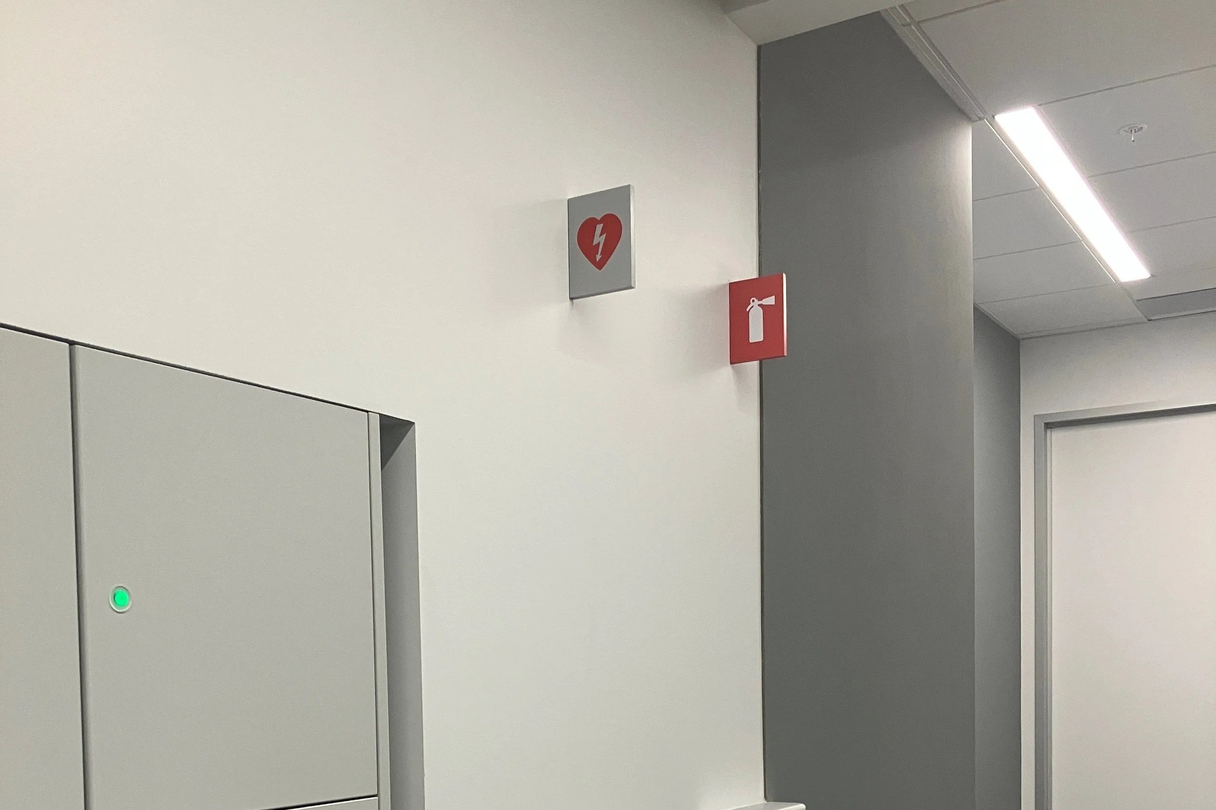 Installed AED blade signage mounted above emergency equipment for code-compliant life safety identification at the KPMG San Jose office.