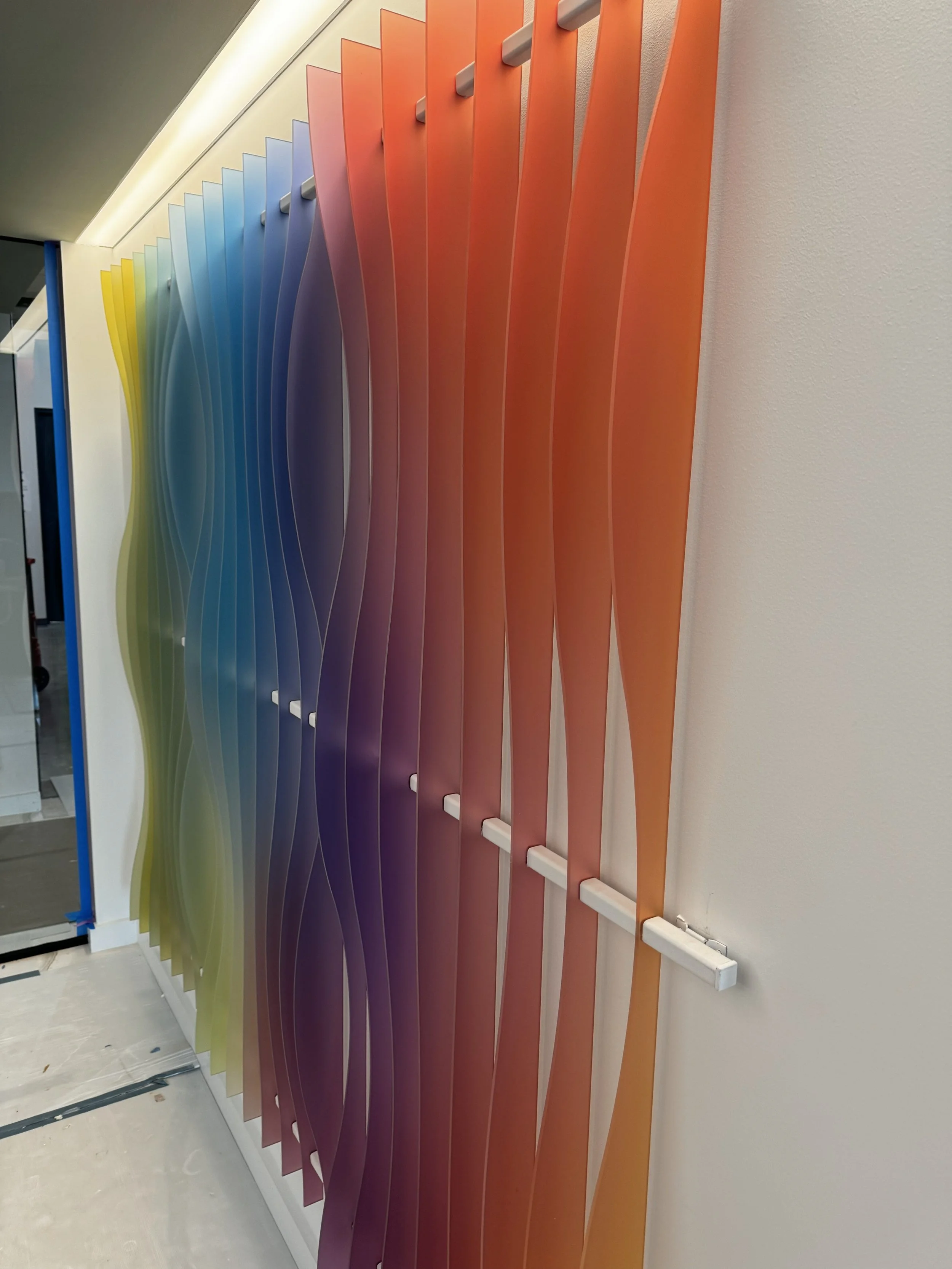 Right angle view of installed custom acrylic 3D feature wall with gradient color panels in the KPMG reception area in Minneapolis, Minnesota.
