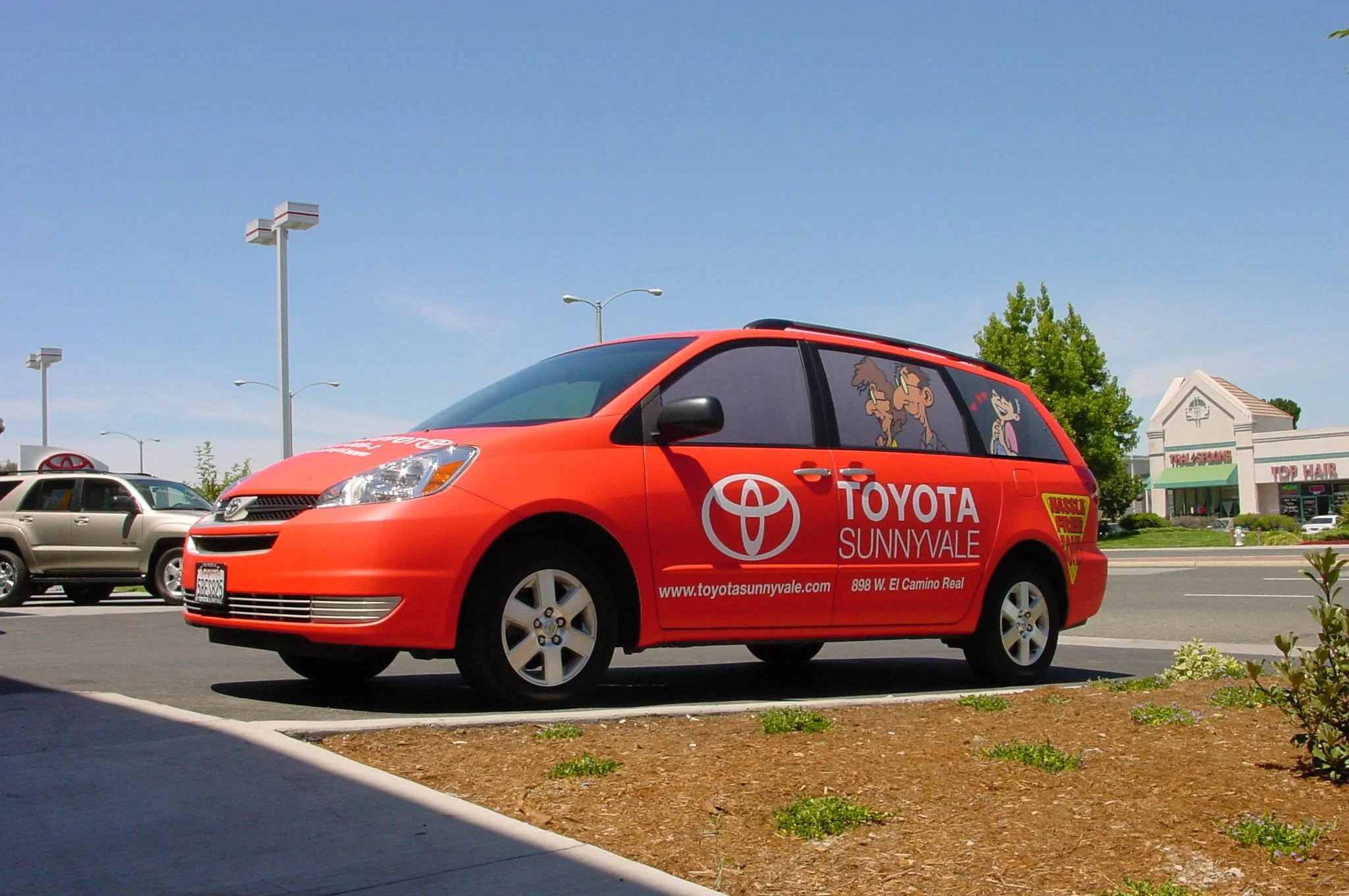 Red Toyota service car with full custom vehicle wrap featuring company branding and contact information.