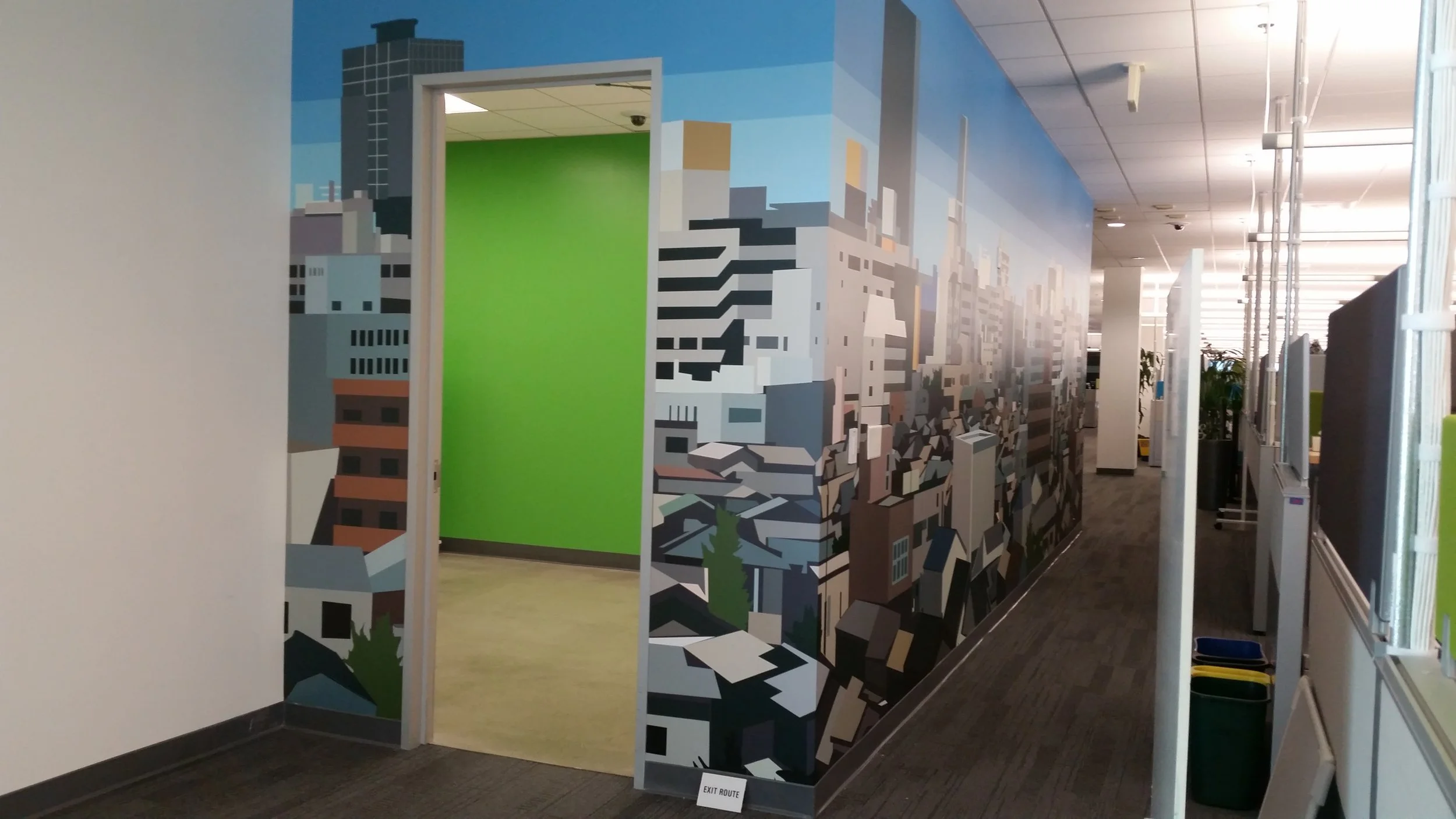 Cityscape mural wallcovering installed near an office entry to reinforce location-based branding.