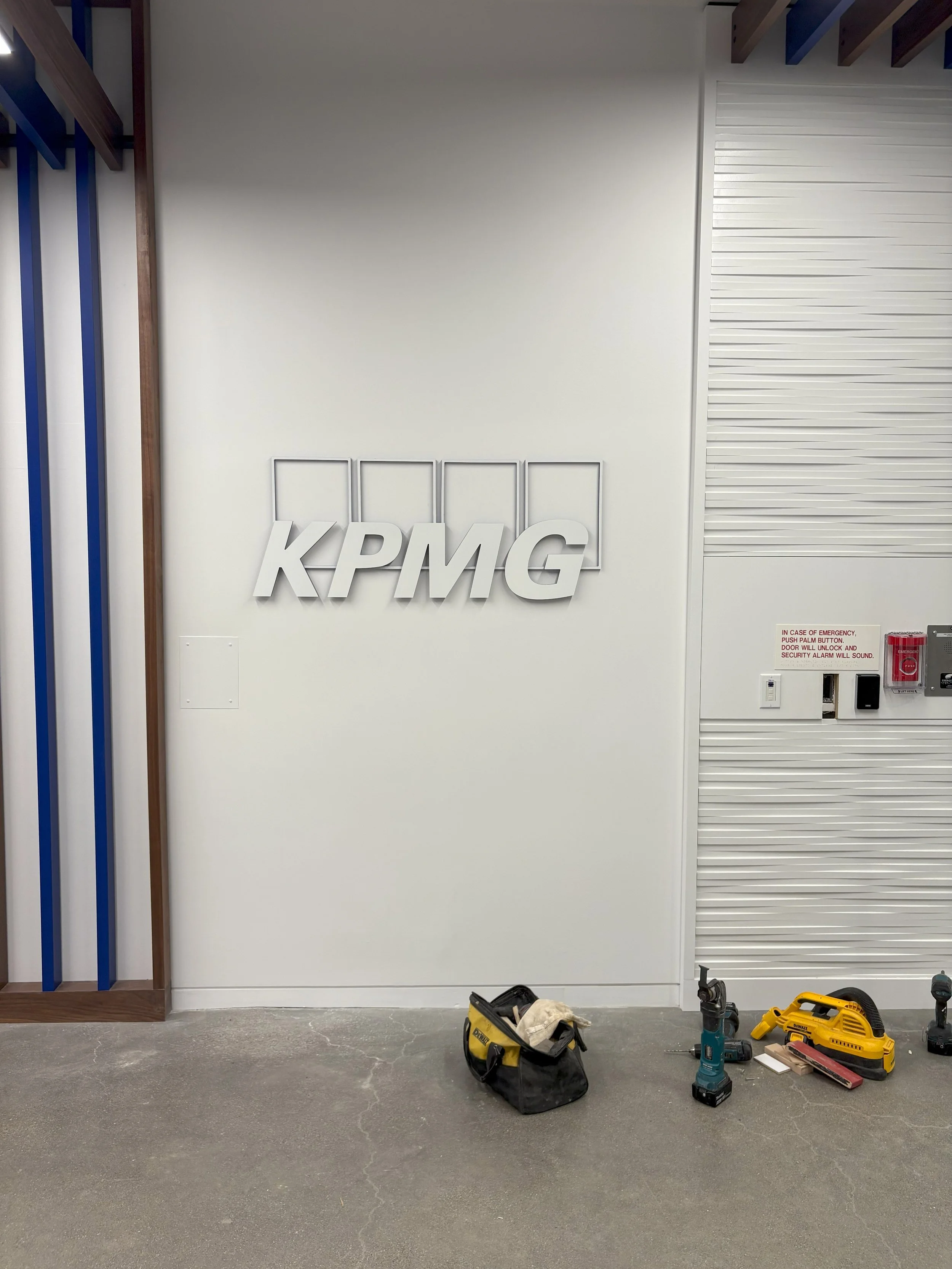Dimensional KPMG logo signage installation in progress on feature wall at the KPMG San Jose office.