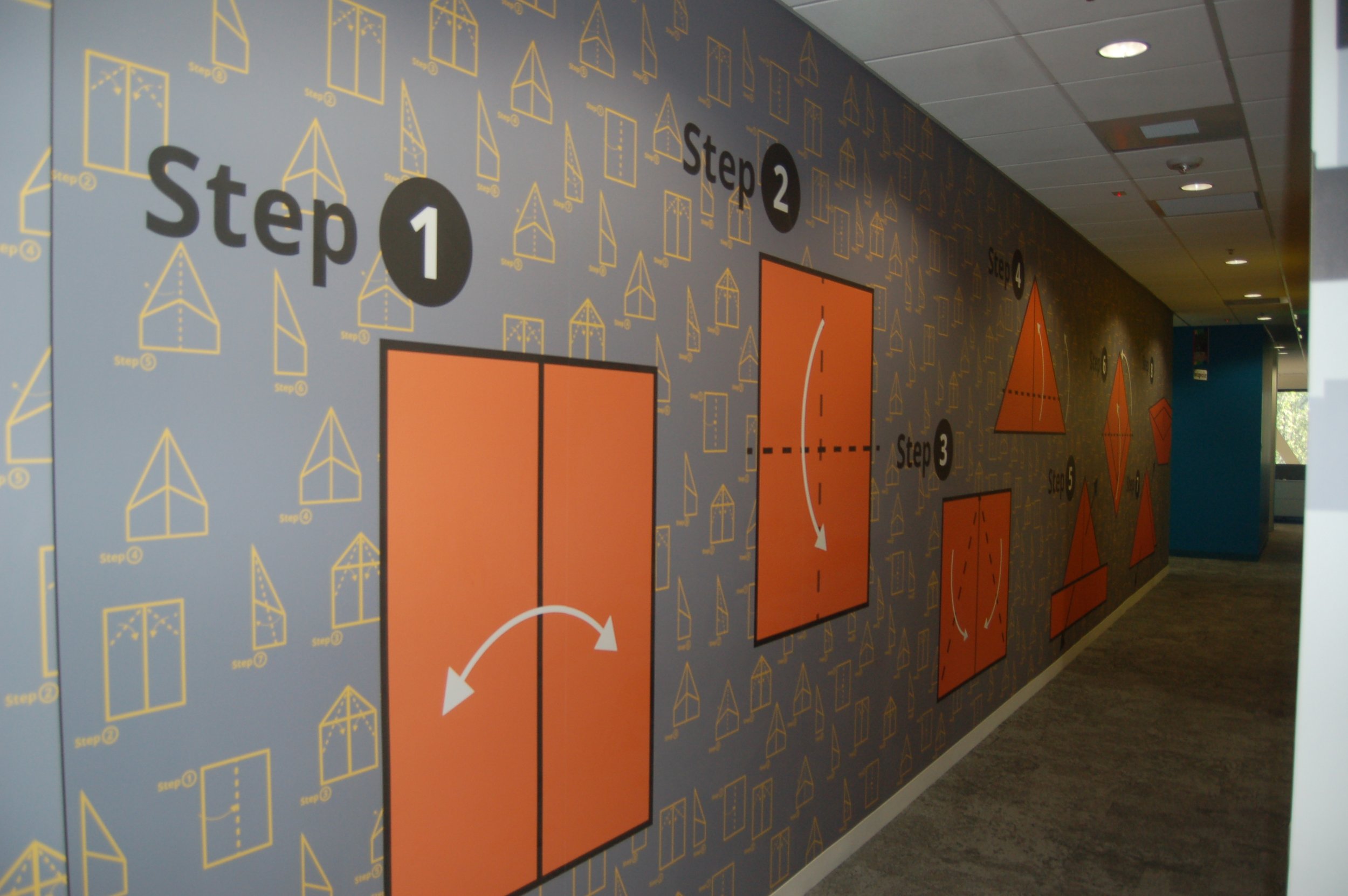Branded environmental graphics with room identification and messaging applied to a corporate corridor.