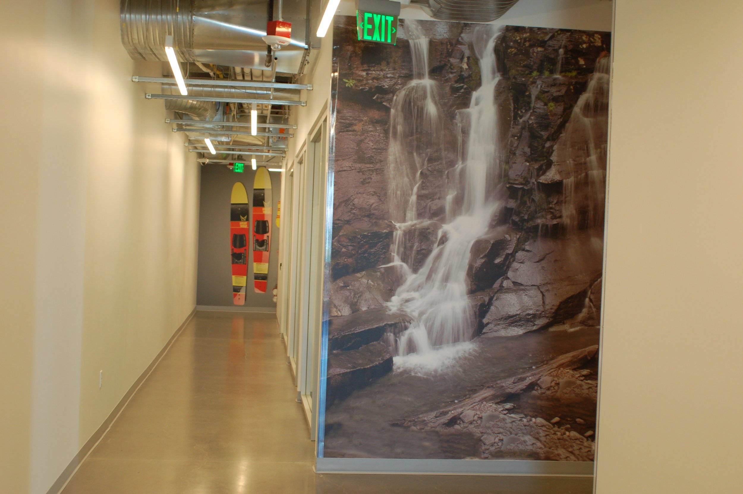 Large-format waterfall mural wallcovering installed along a hallway to create a dramatic environmental graphic.