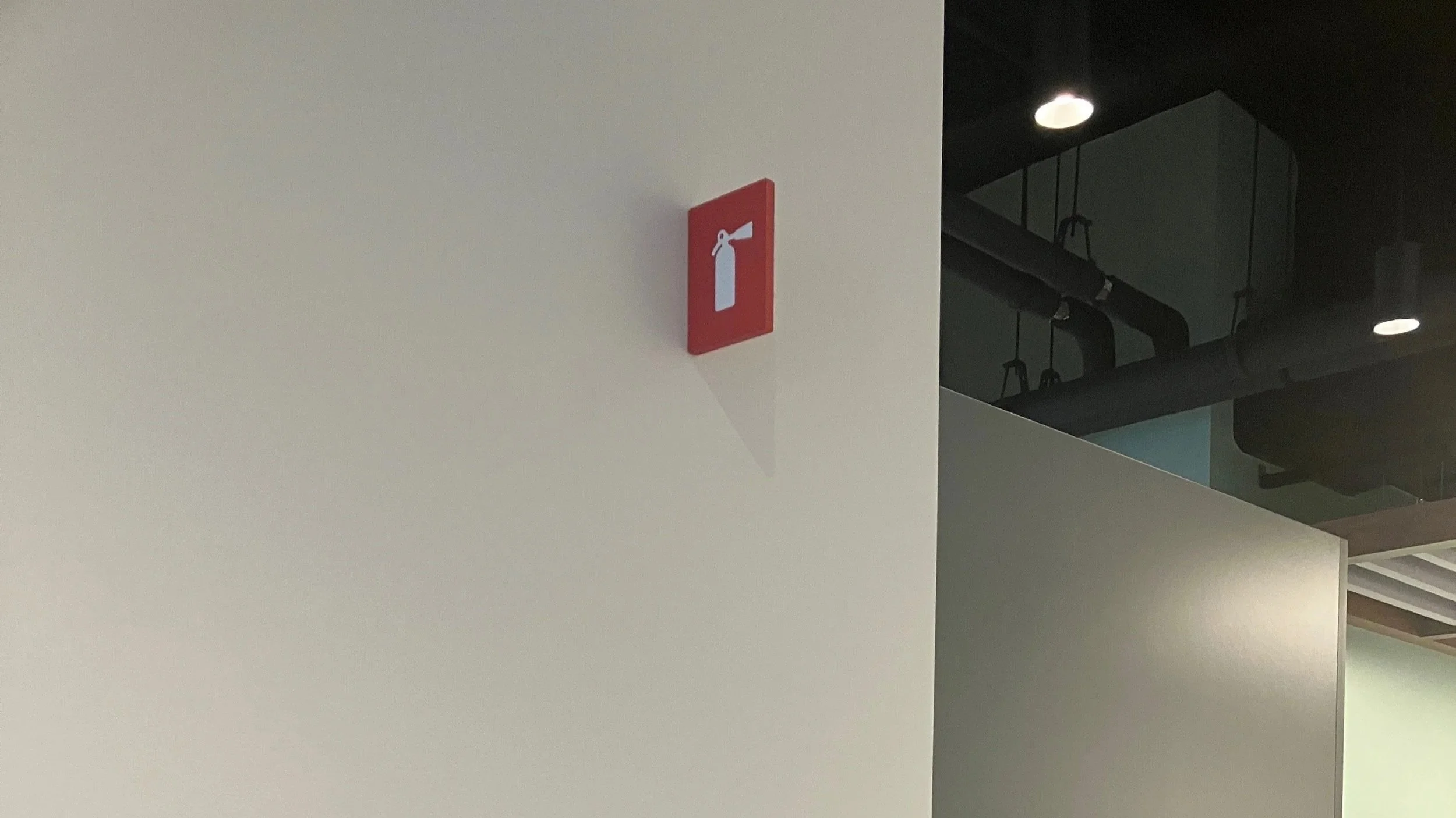 Installed fire extinguisher blade signage mounted on wall for code-compliant life safety identification at the KPMG San Jose office.