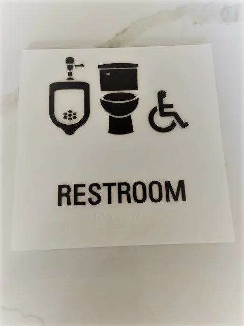 ADA-compliant restroom signage with tactile symbols and braille for accessibility in commercial facility