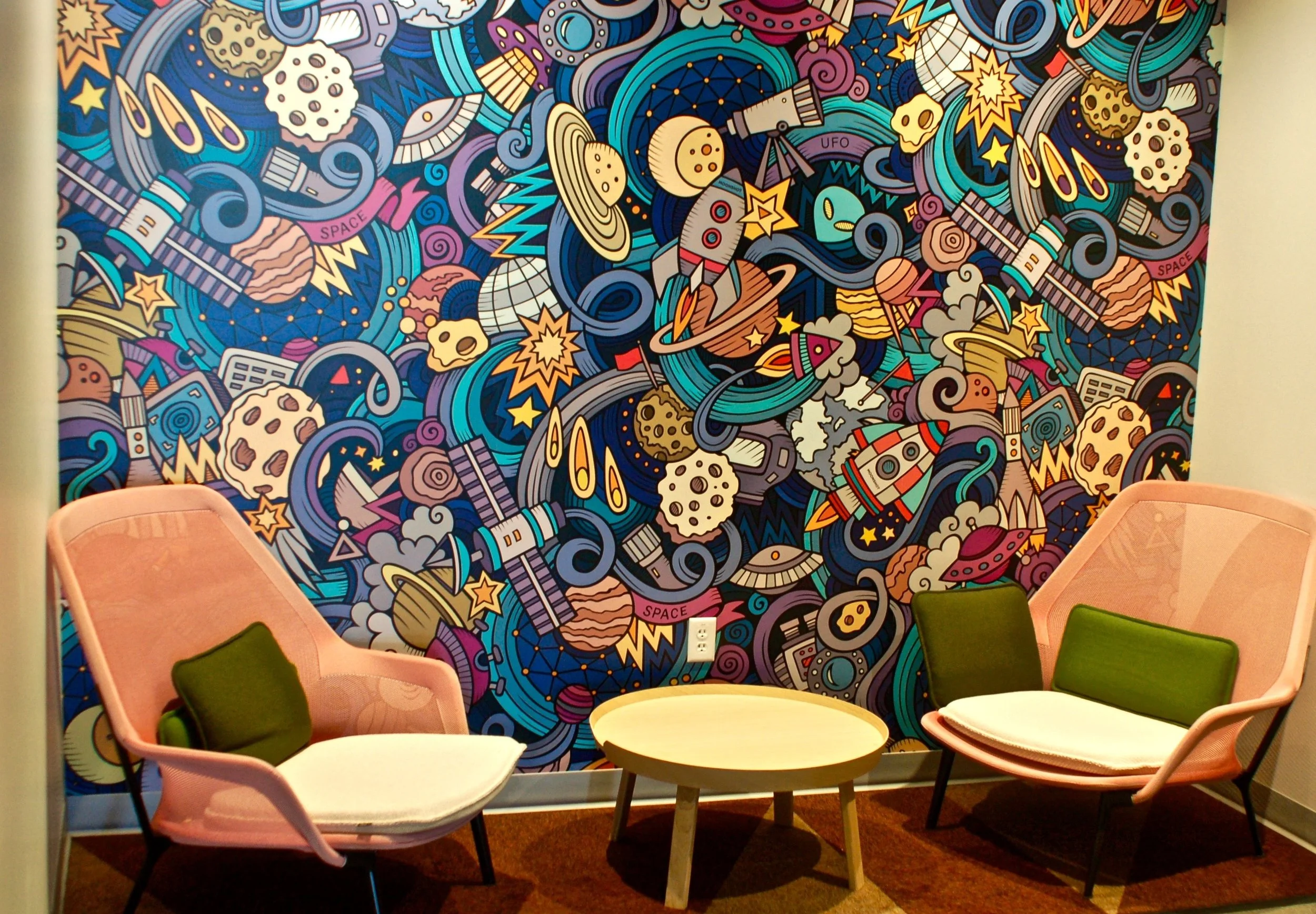 Colorful custom mural wallcovering creating a bold feature wall in a collaborative seating area.