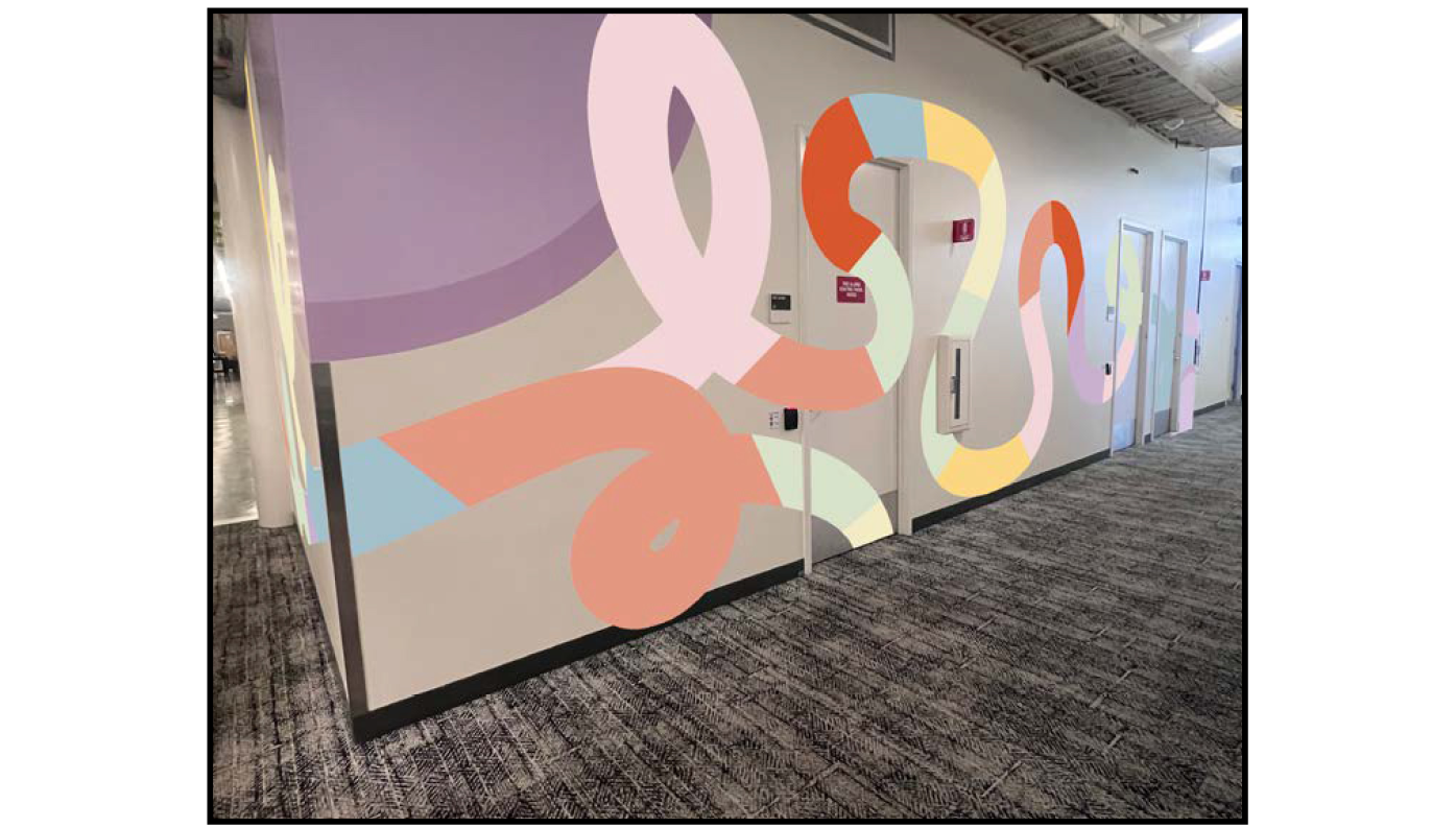 Colorful abstract environmental graphics wall wrap installed along office hallway with integrated doors for workplace branding project
