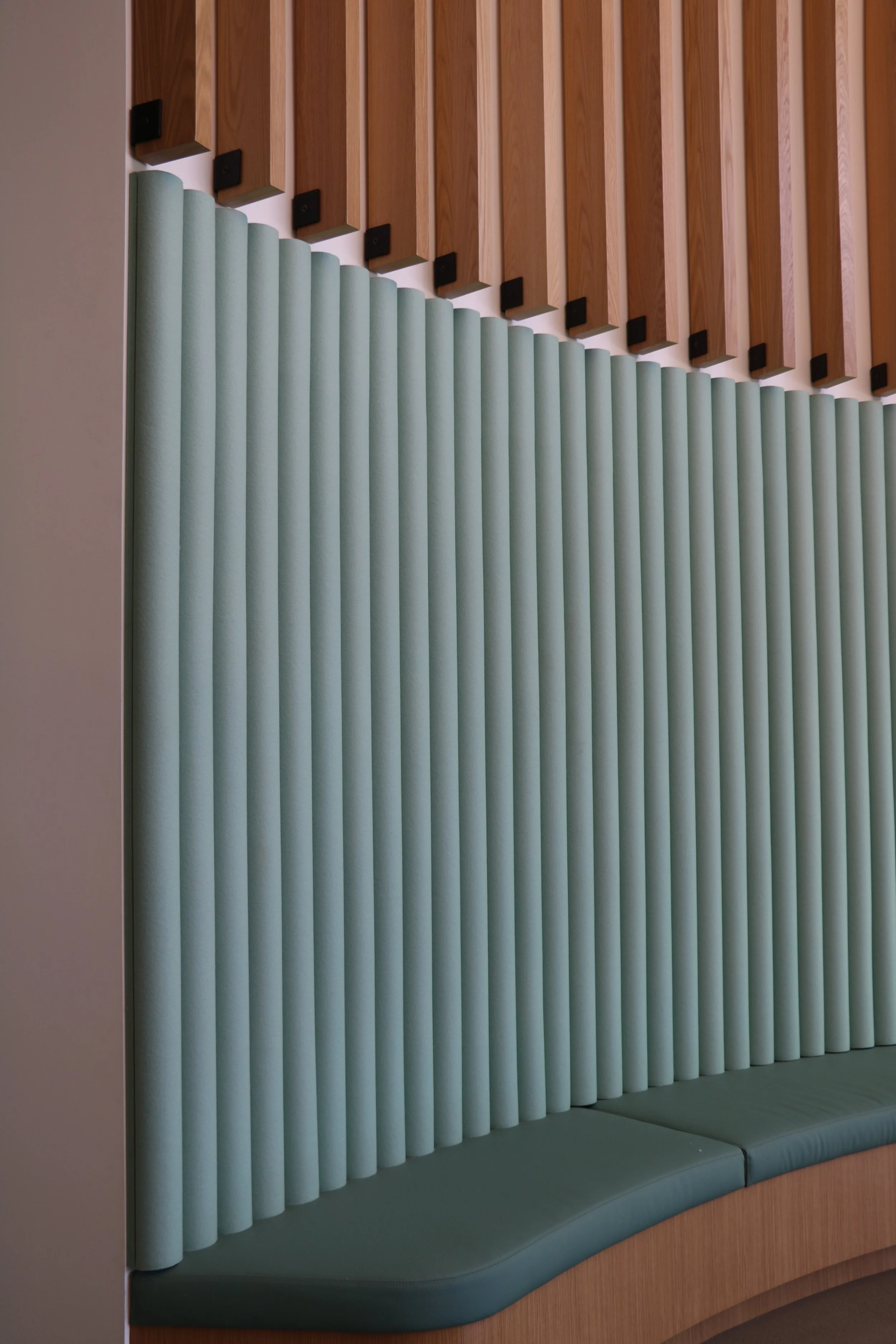 Vertical acoustic felt wall panels in soft green tone featuring FilzFelt ARO Plank system for commercial interior sound control.