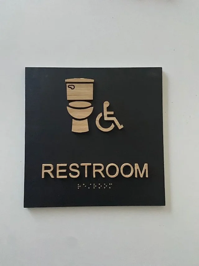 Dimensional restroom identification signage designed for clear navigation in commercial workplace