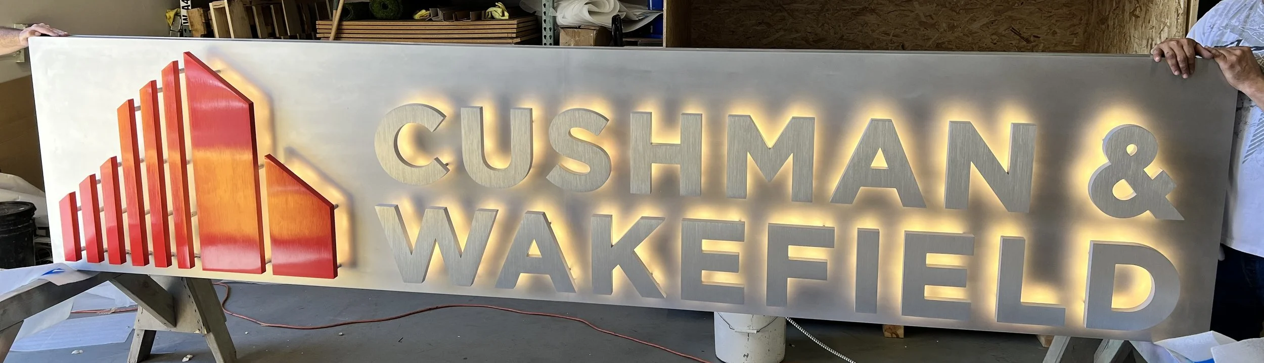 Illuminated Cushman & Wakefield dimensional signage creating a bold branded feature within commercial space
