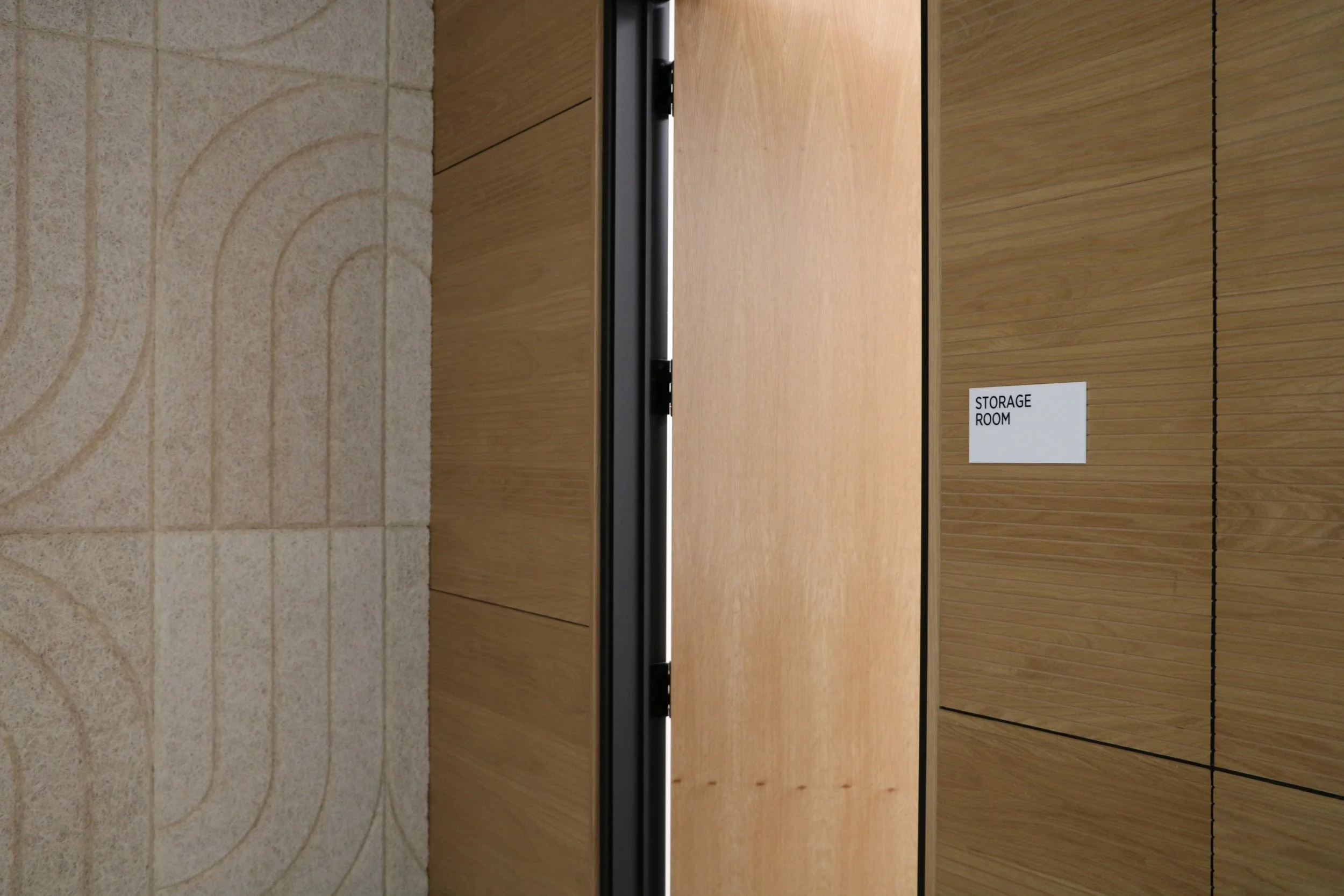 BAUX Wood Wool Curve acoustic panels installed alongside wood veneer doors in modern commercial office interior.