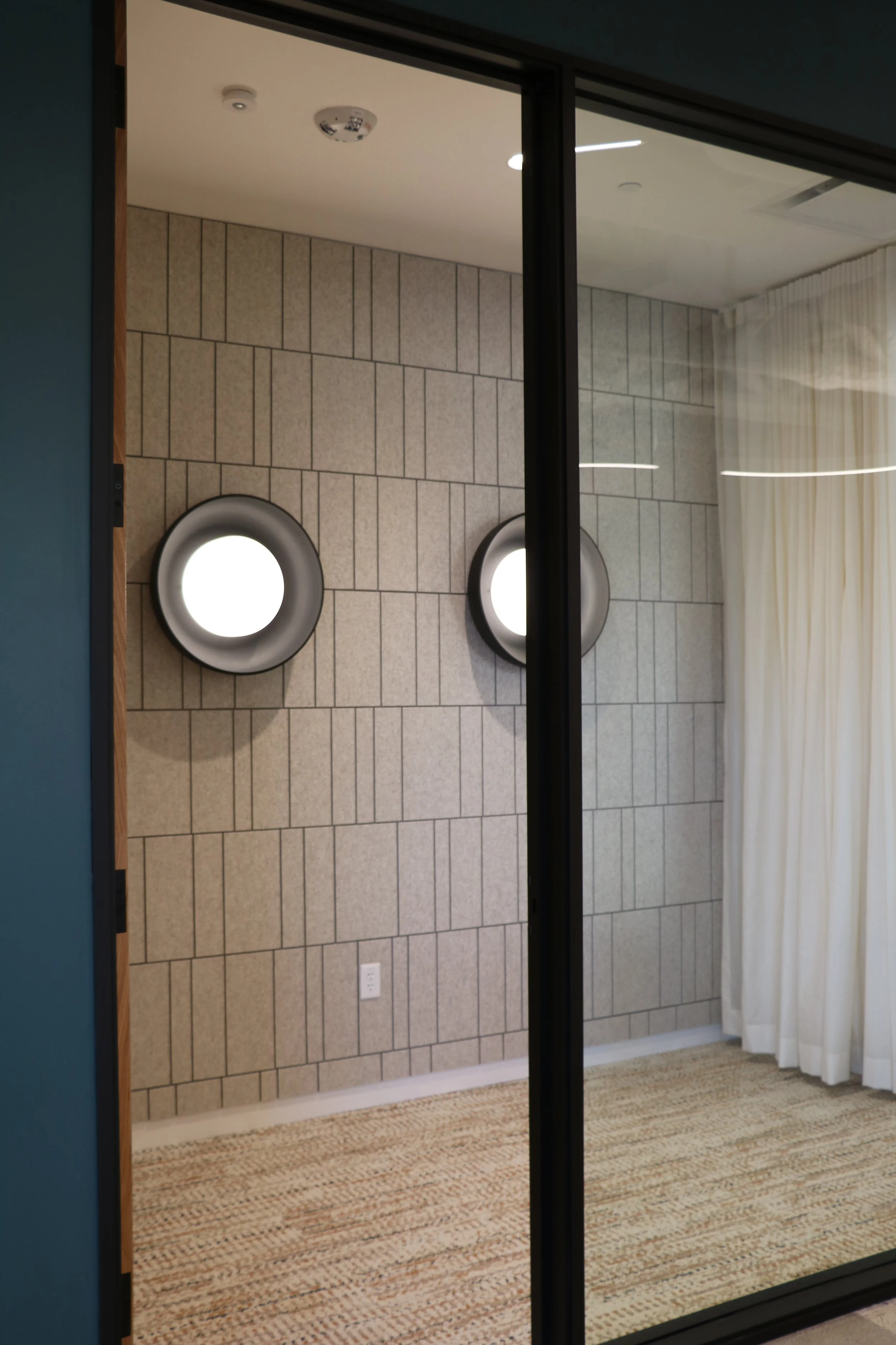 Patterned acoustic wall panels installed behind glass to improve sound control and privacy in meeting room environment