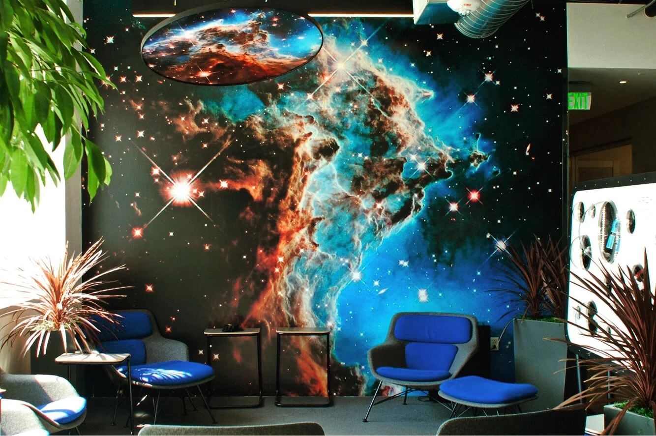 Galaxy-themed immersive mural wallcovering creating a bold experiential feature wall in a collaborative space.