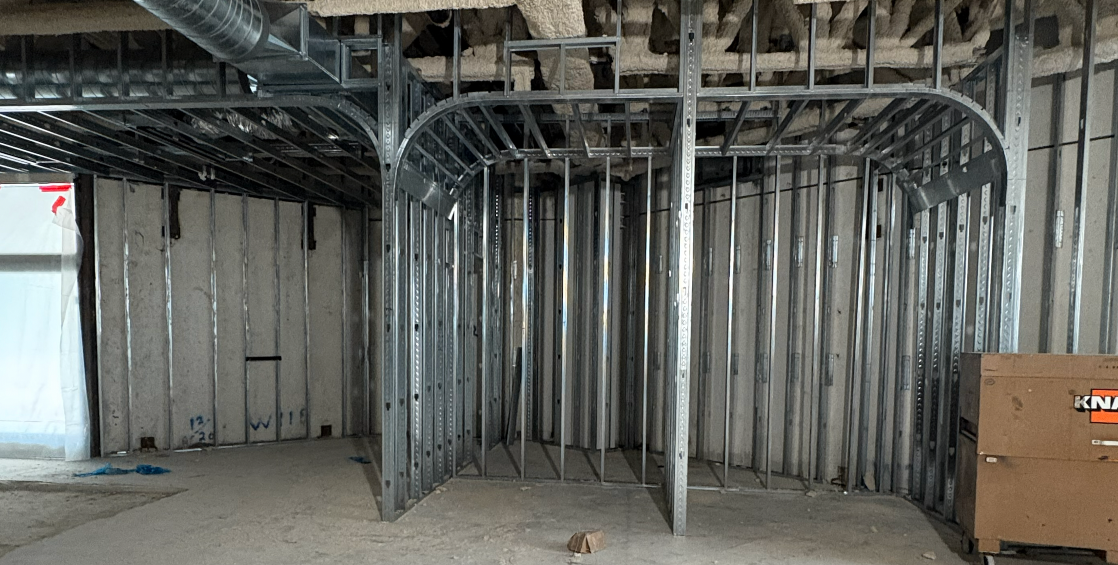 Commercial interior under construction with metal stud framing prepared for BAUX wood wool acoustic panel installation.