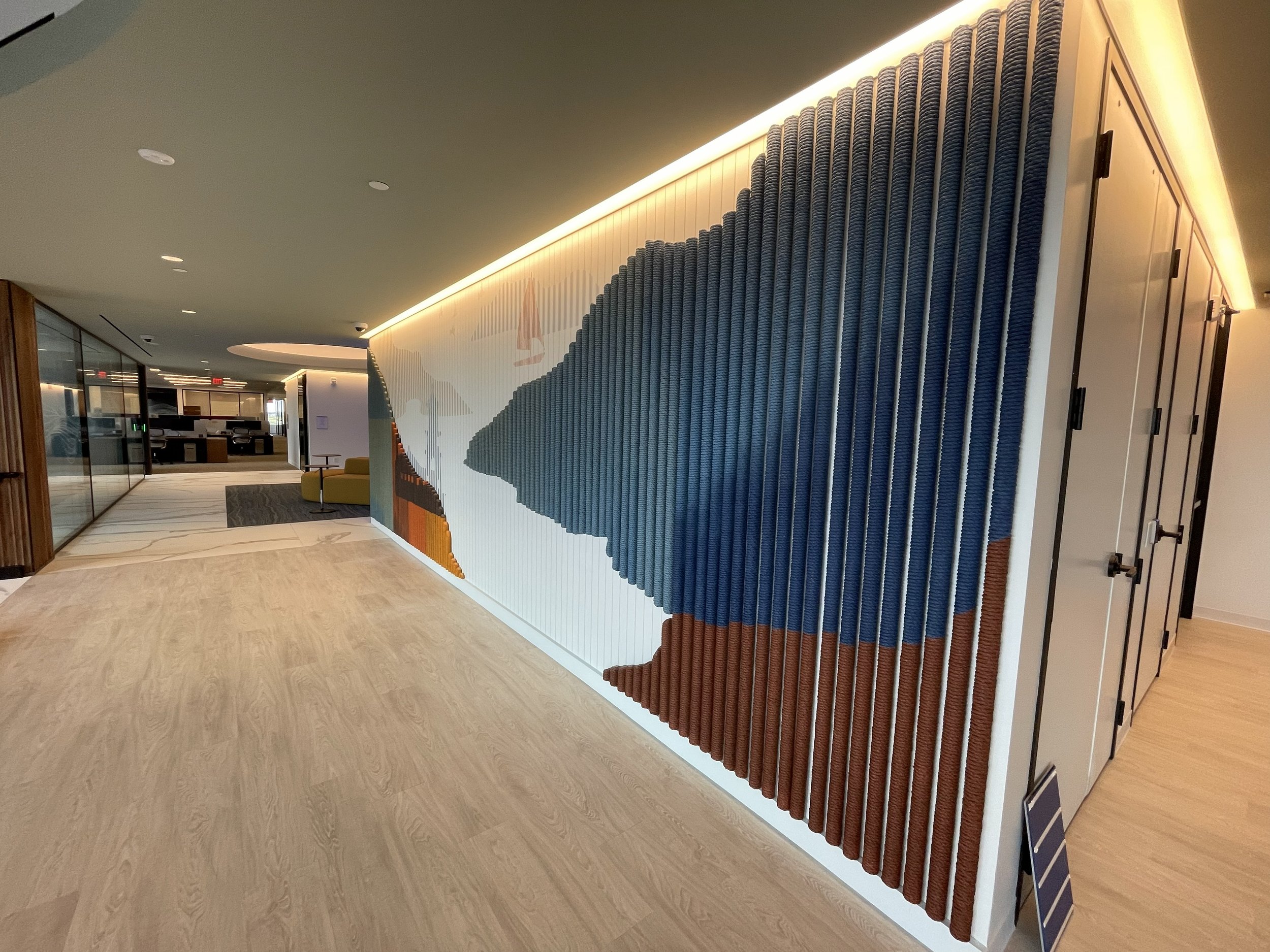 Angled corridor view of custom textured wallcovering with dimensional rope elements wrapping a corner feature wall at KPMG office in Minneapolis, Minnesota.