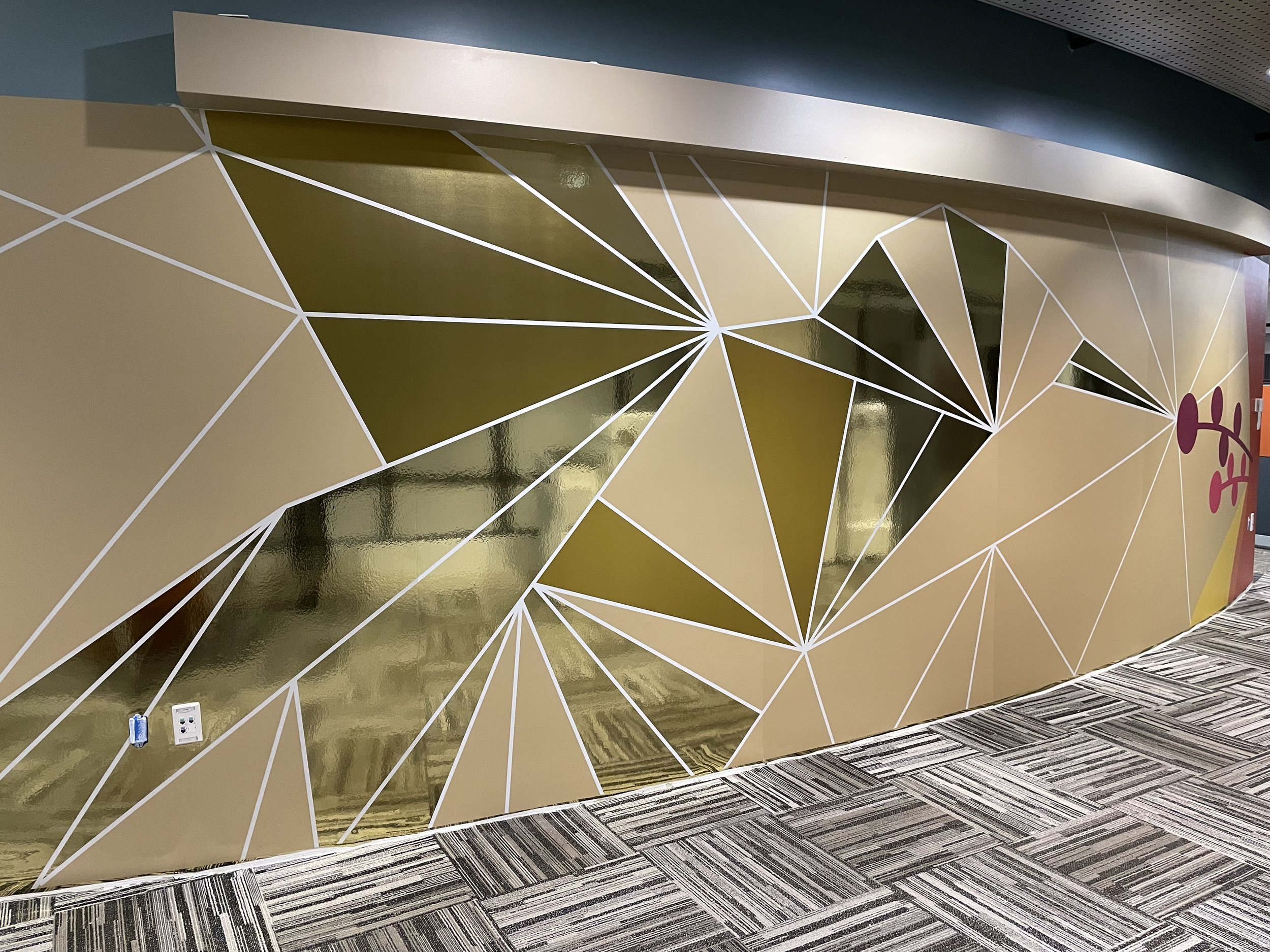 Close-up view of curved geometric metallic wallcovering with faceted reflective panels installed at Amazon SJC3 office, fabricated and installed by JP Digital in Cupertino, California.