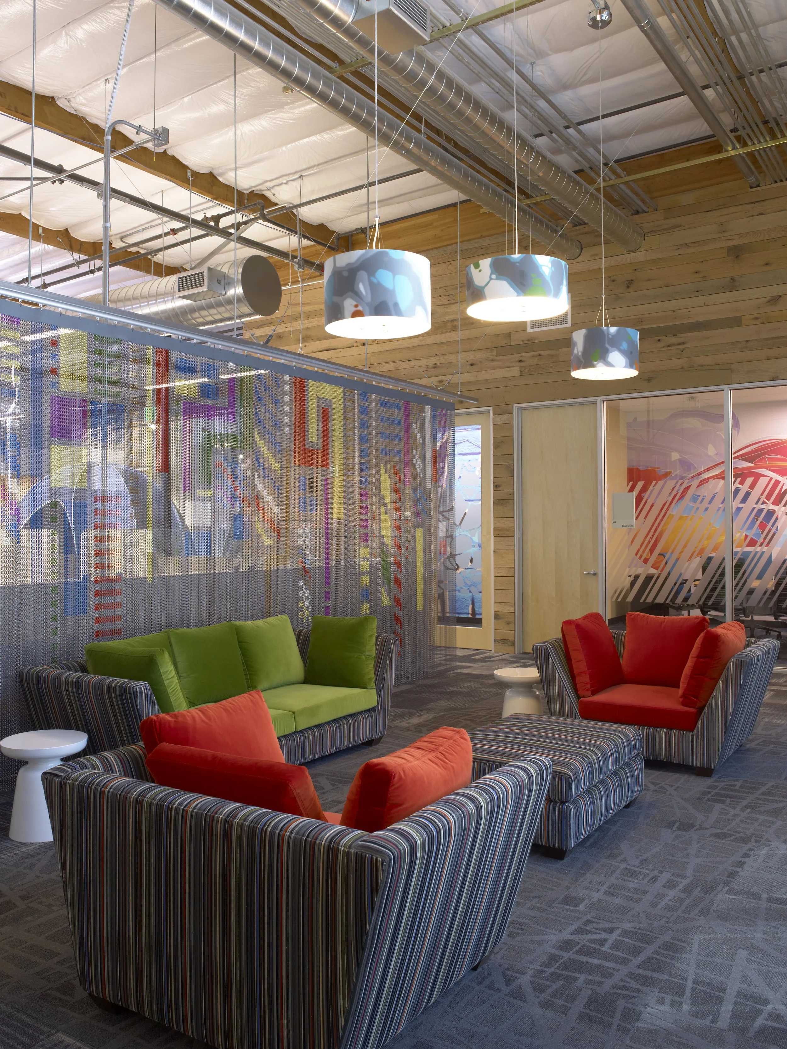 Custom printed wallcoverings and graphics enhancing a creative office lounge with branded interior design elements.