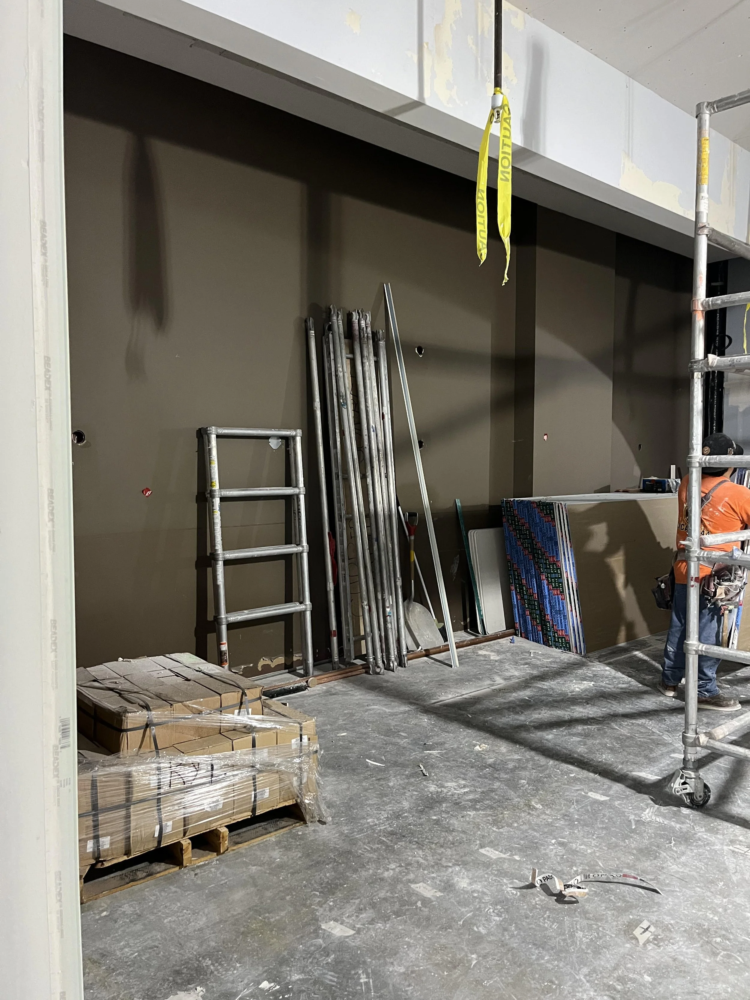 Pre-construction commercial interior wall and corridor with exposed framing, drywall installation in progress, and surfaces prepared for future finishes, signage, or wallcovering.