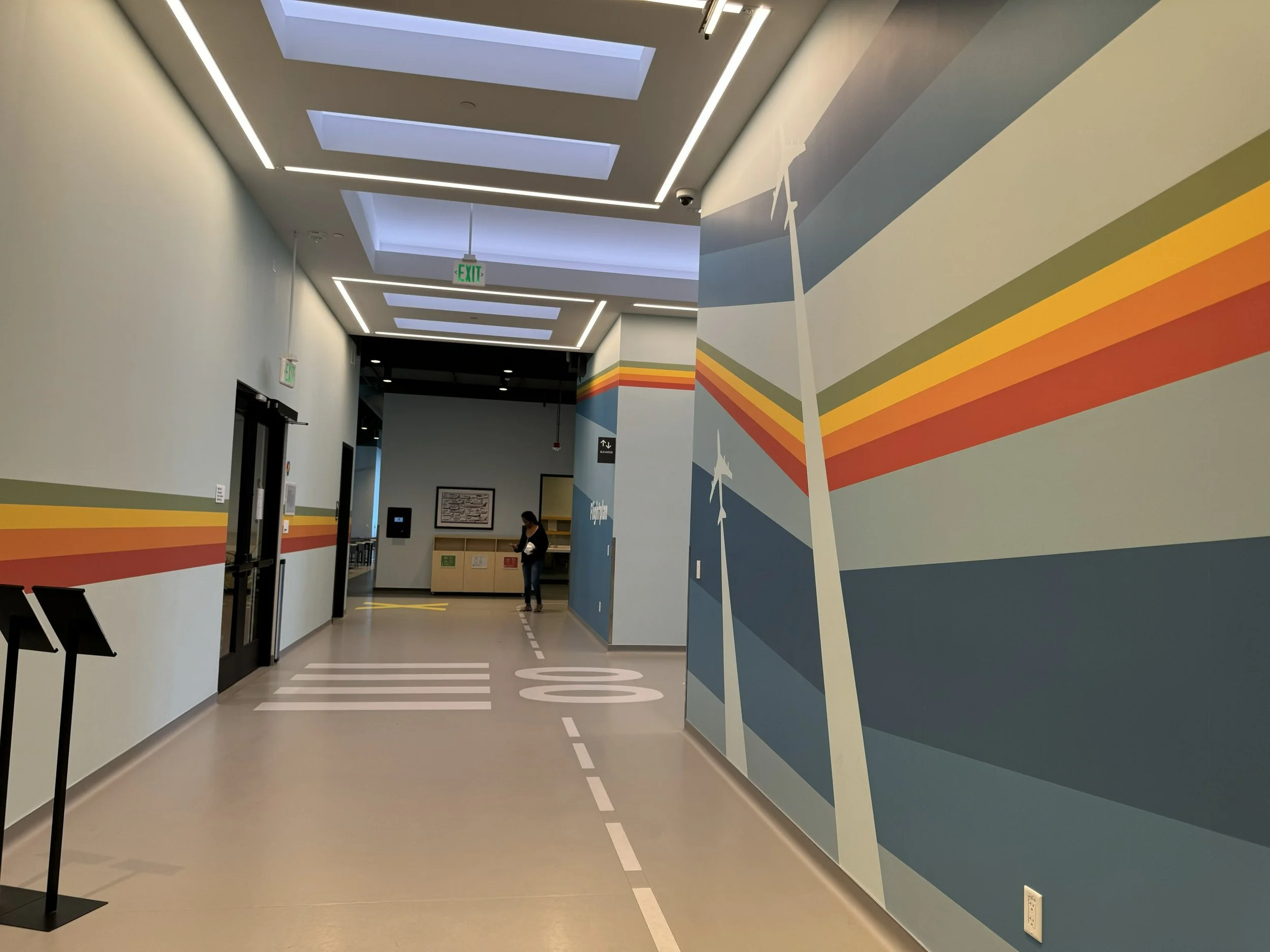 Color-coded corridor graphics and floor striping designed to support intuitive wayfinding and circulation.