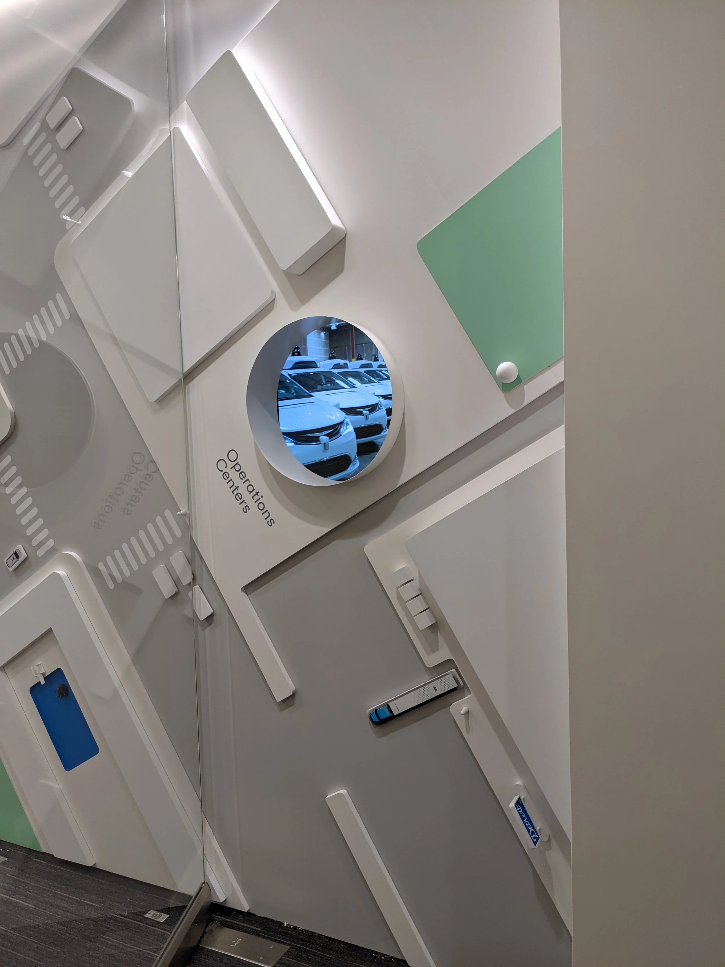 Layered dimensional wall installation combining geometric forms and brand elements for a sculptural interior feature.