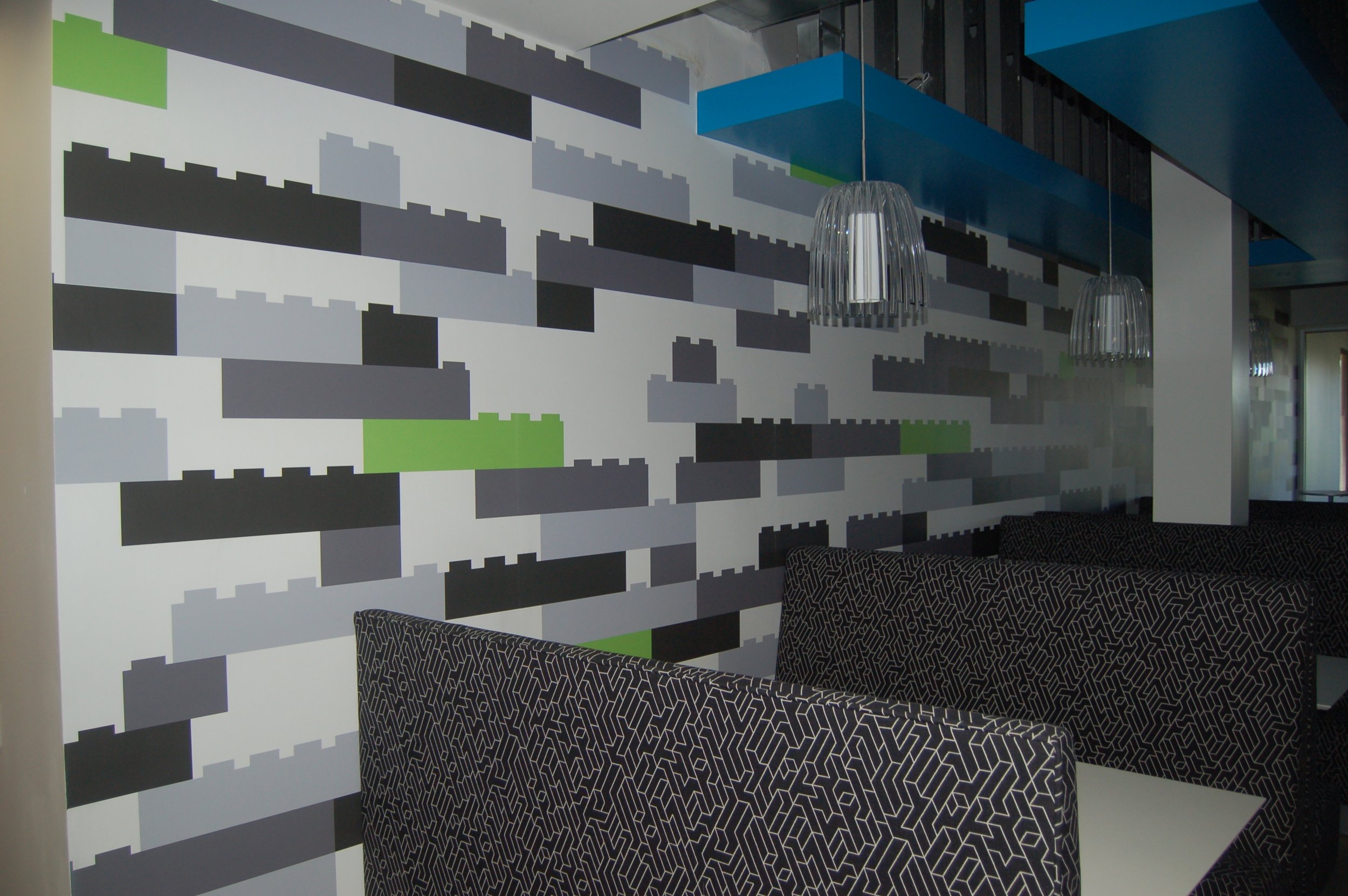 Geometric dimensional-look wallcovering creating a modern textured feature wall in an office environment.