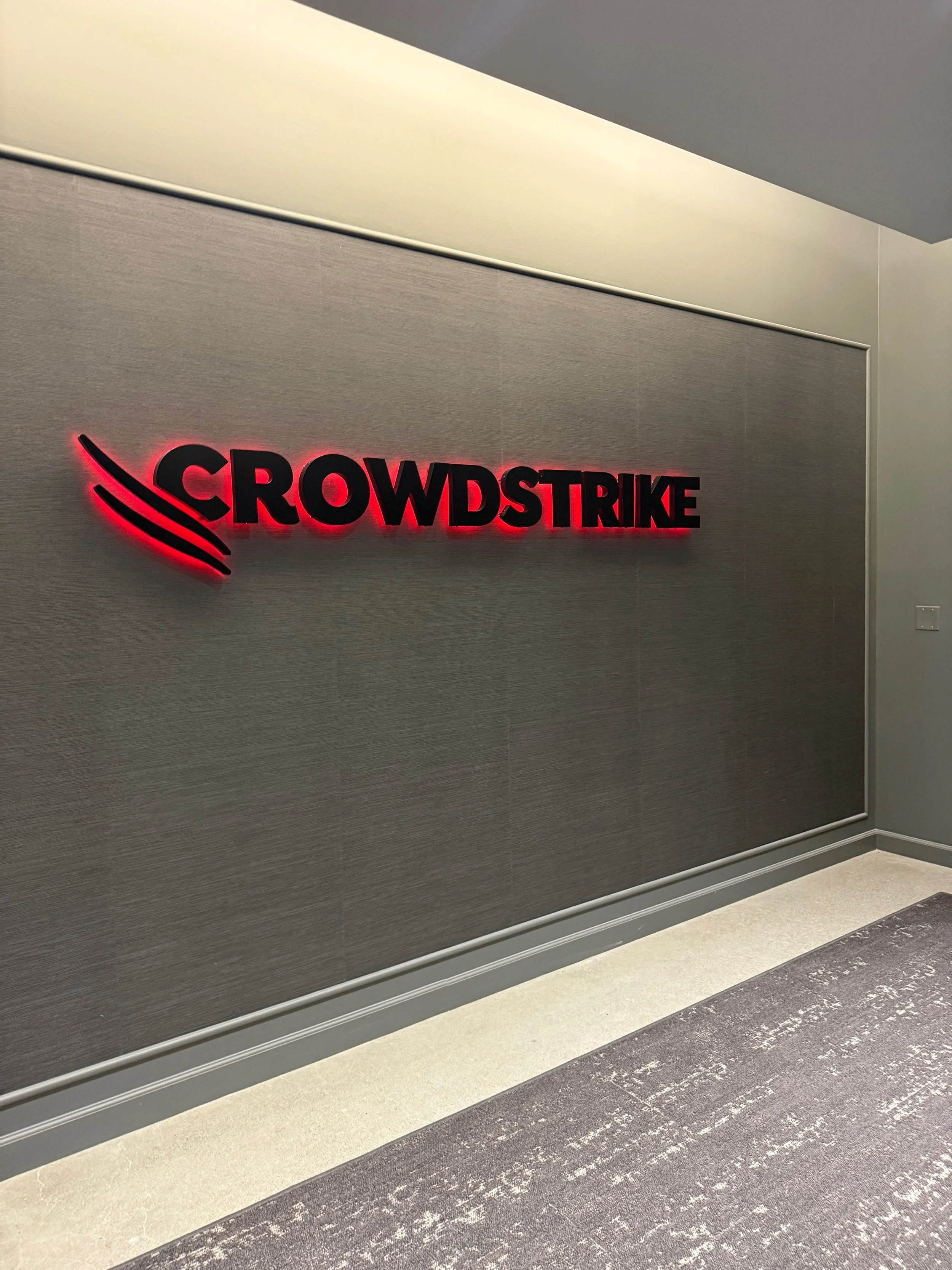 Illuminated CrowdStrike dimensional logo signage installed to create a bold branded feature in corporate office environment