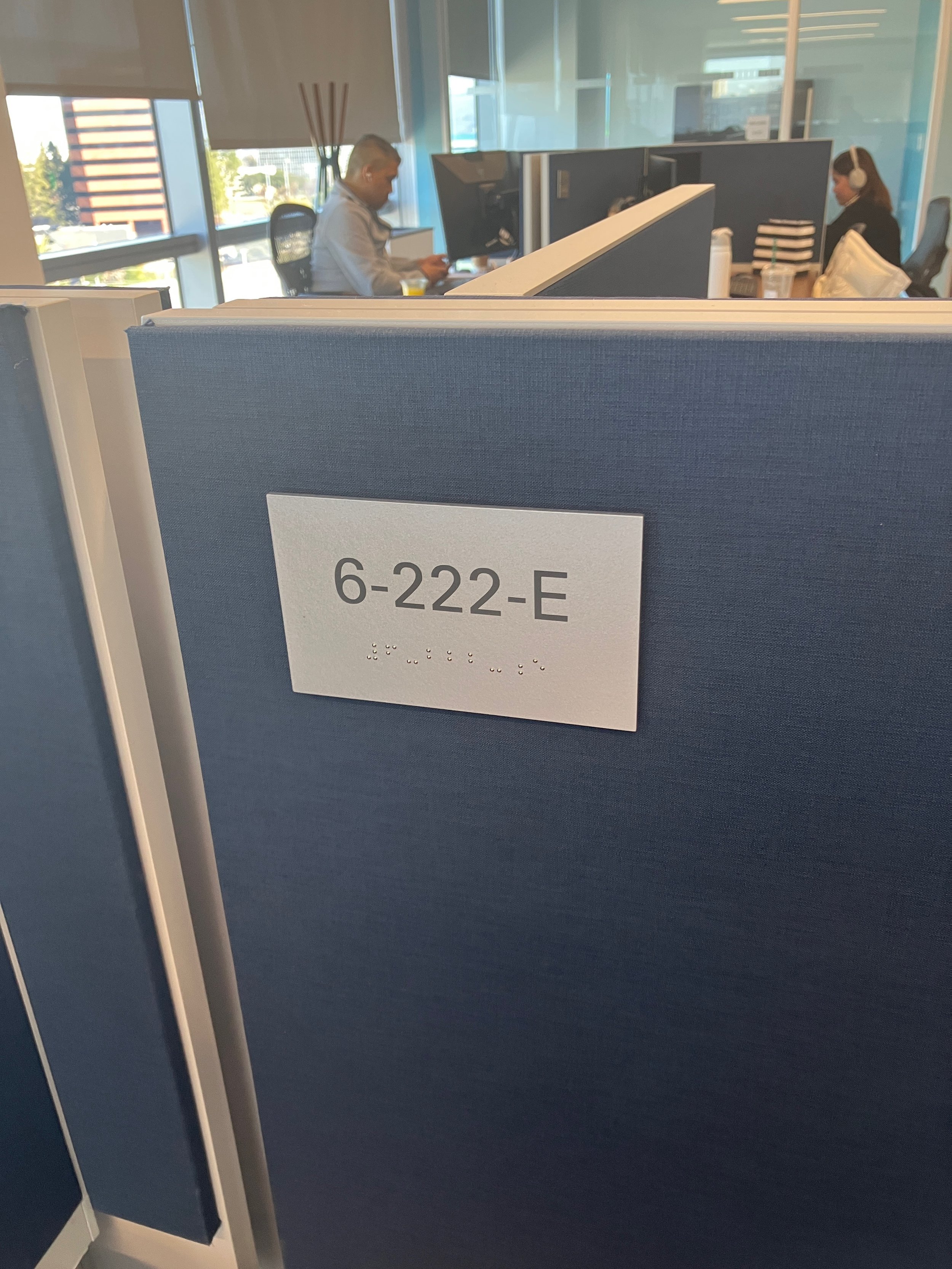 ADA-compliant cubicle nameplate with braille installed for workstation identification at the KPMG San Jose office.