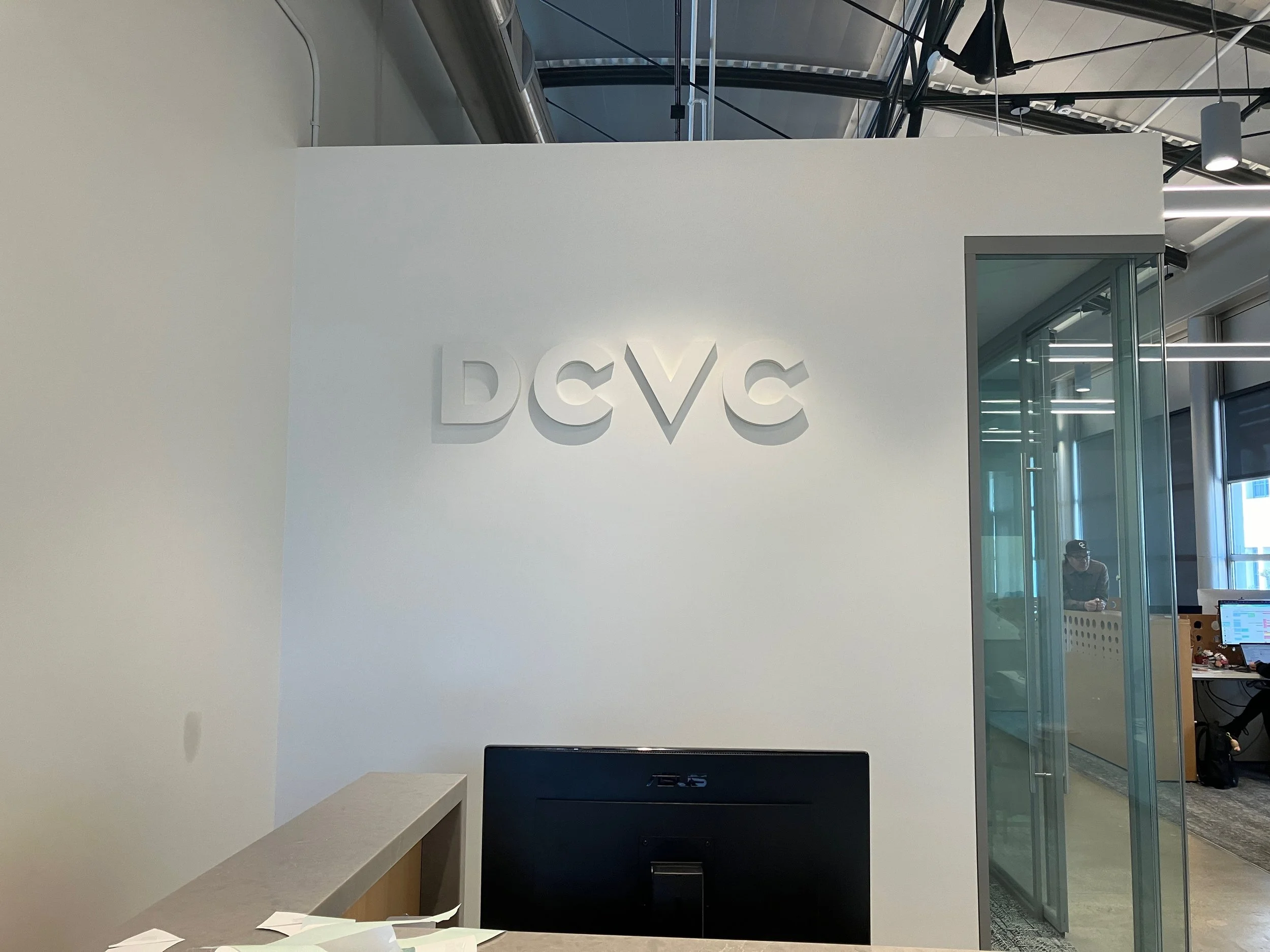 DCVC dimensional wall logo installed in modern office interior with backlit corporate branding signage.