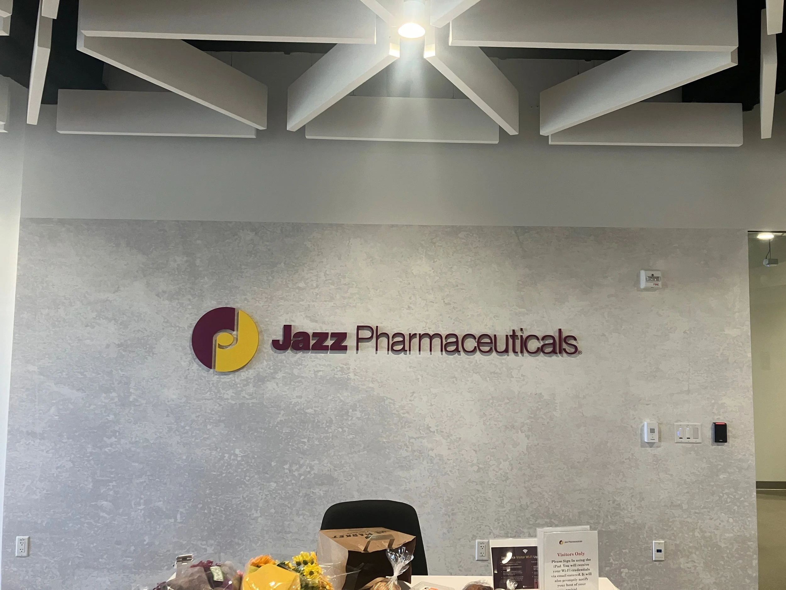 Installed dimensional Jazz Pharmaceuticals logo on textured feature wall at Palo Alto office reception area.