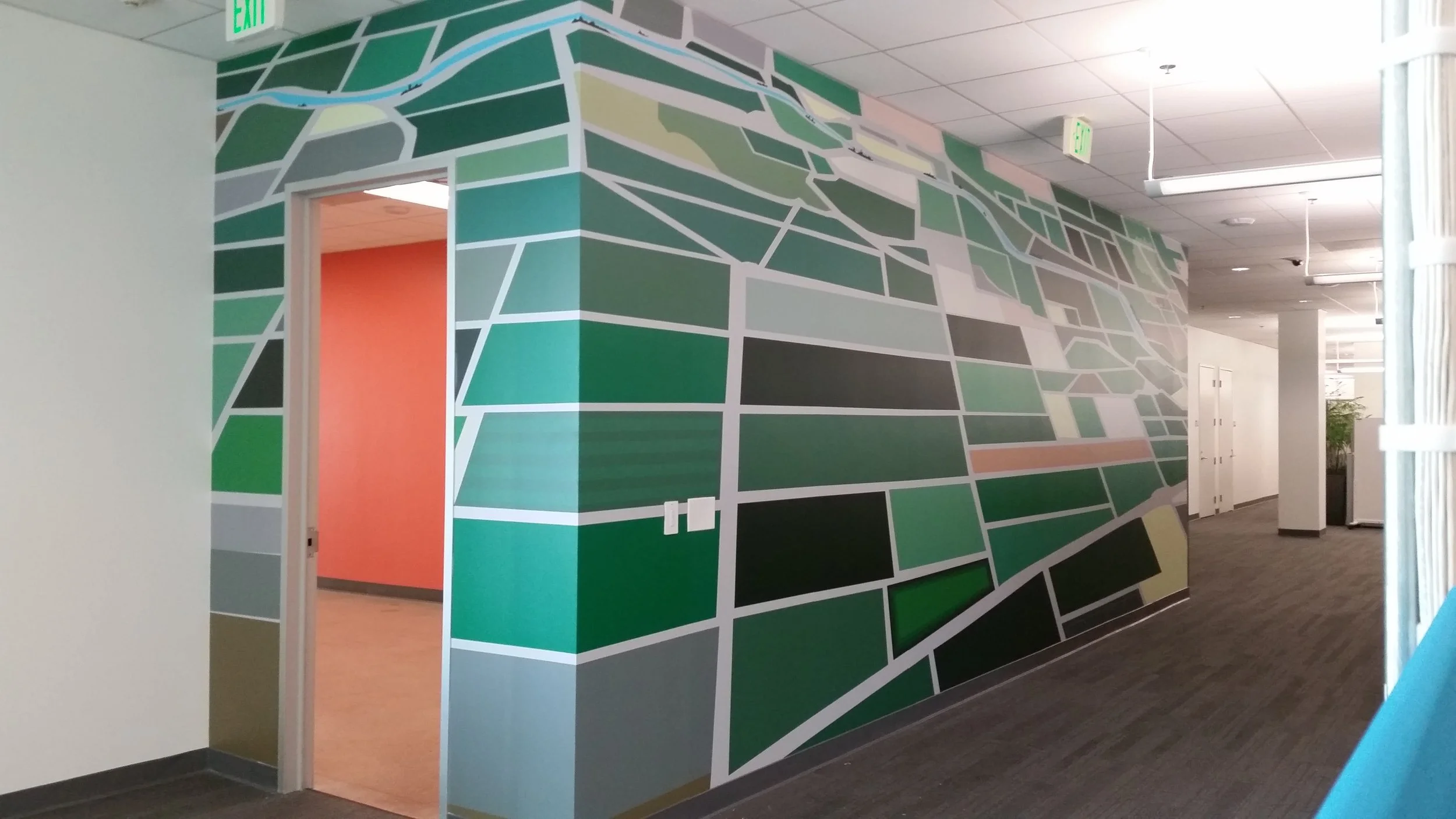 Custom map-style environmental wall graphic wrapping a corridor for wayfinding and visual interest.