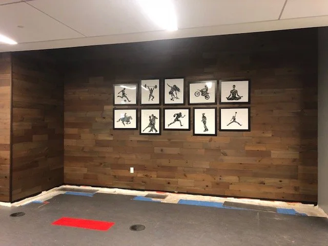 Wood feature wall with framed artwork installed in corporate office interior for a warm architectural finish